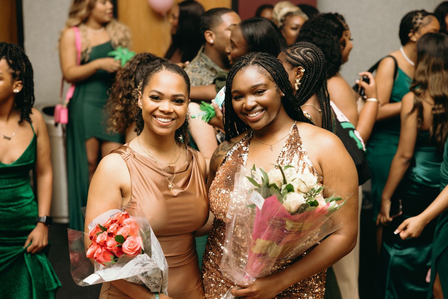 Wedding party wearing green dresses celebrates on dance floor.