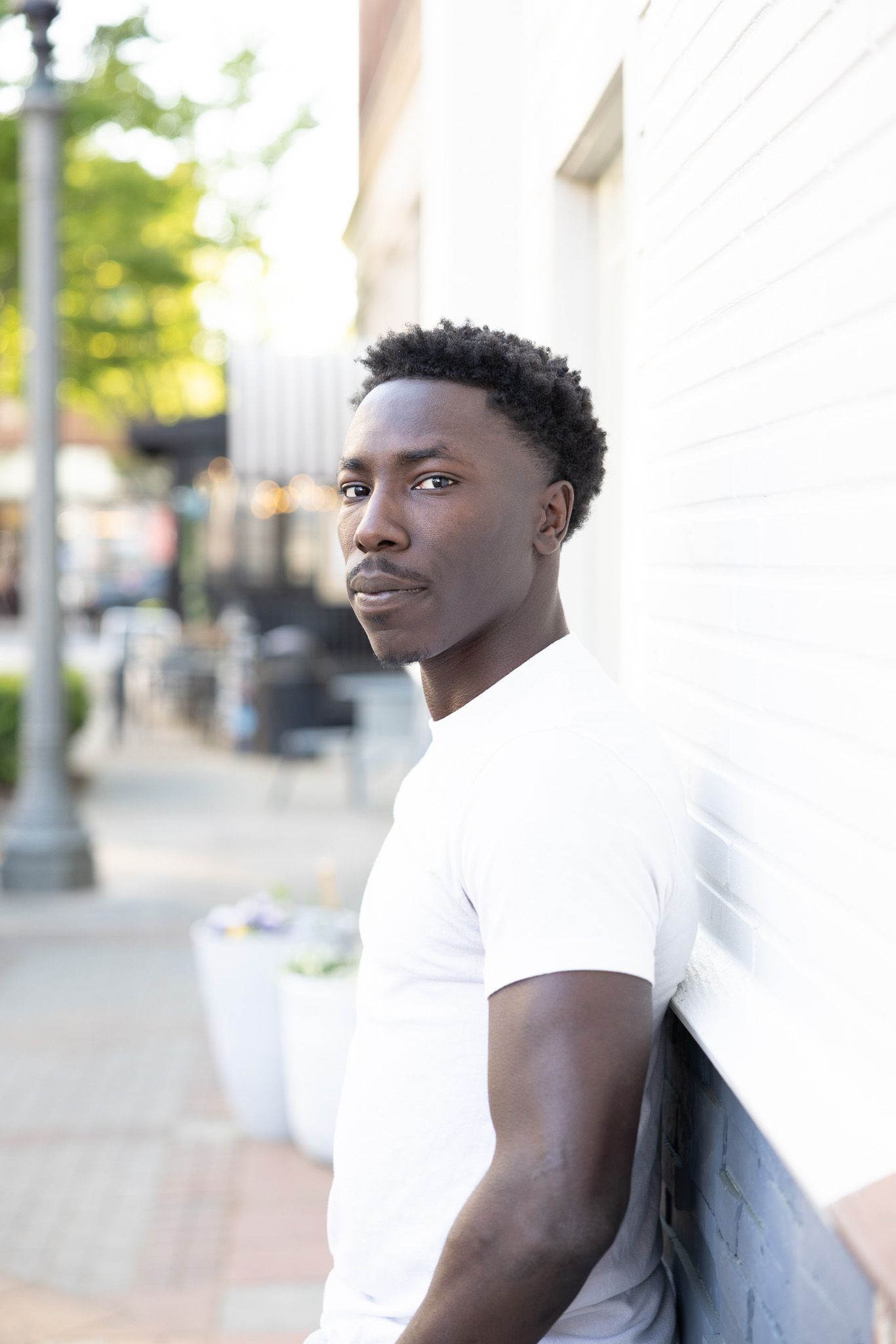 Portrait series of person in white t-shirt against urban backdrop with columns.