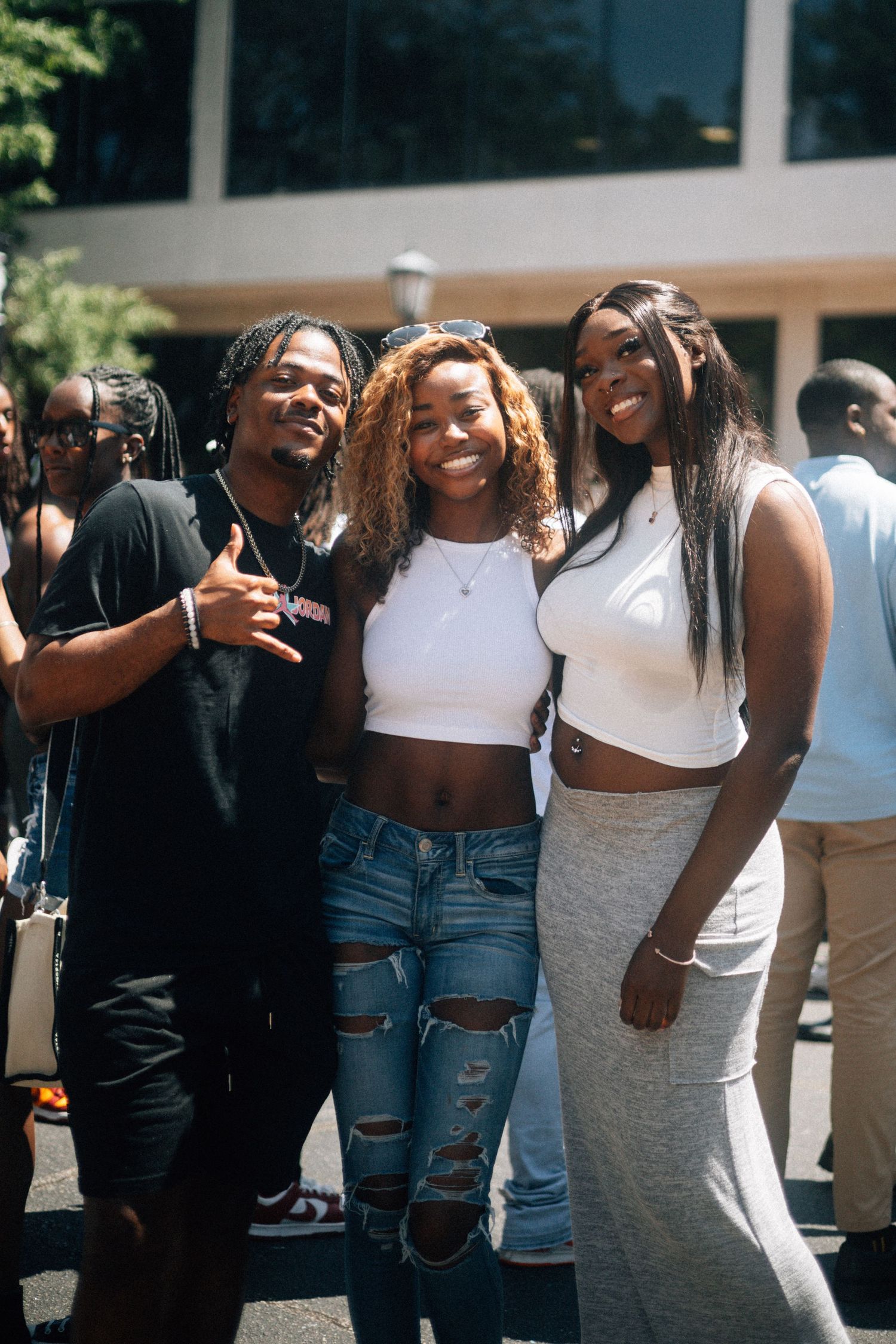 Three smiling friends pose together outside on a sunny day wearing casual outfits including crop tops and ripped jeans.  USC Hip Hop Wednesd