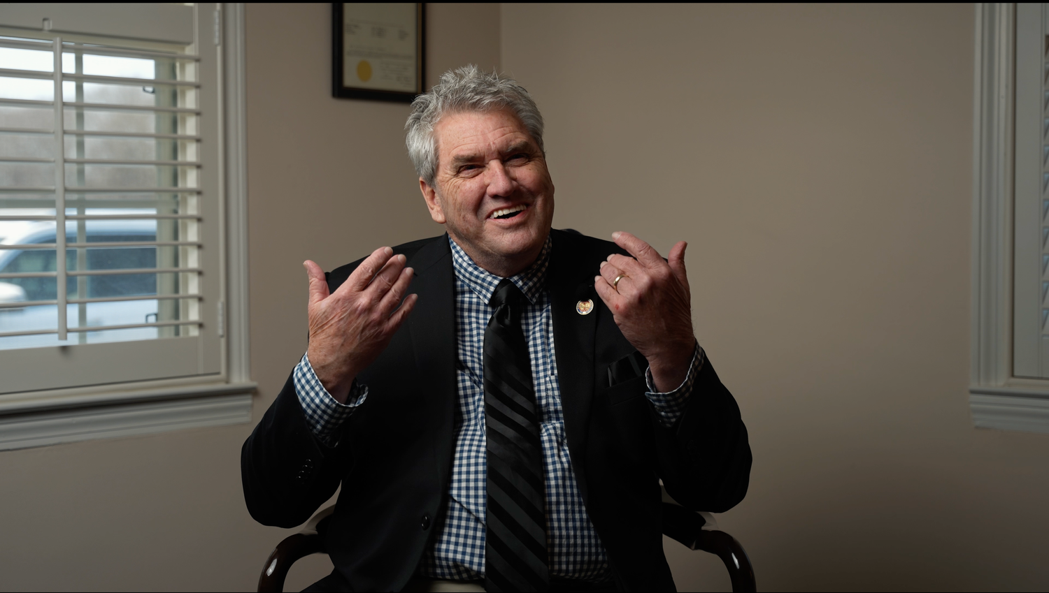 Three sequential photos show someone in a gray suit making expressive gestures while speaking.