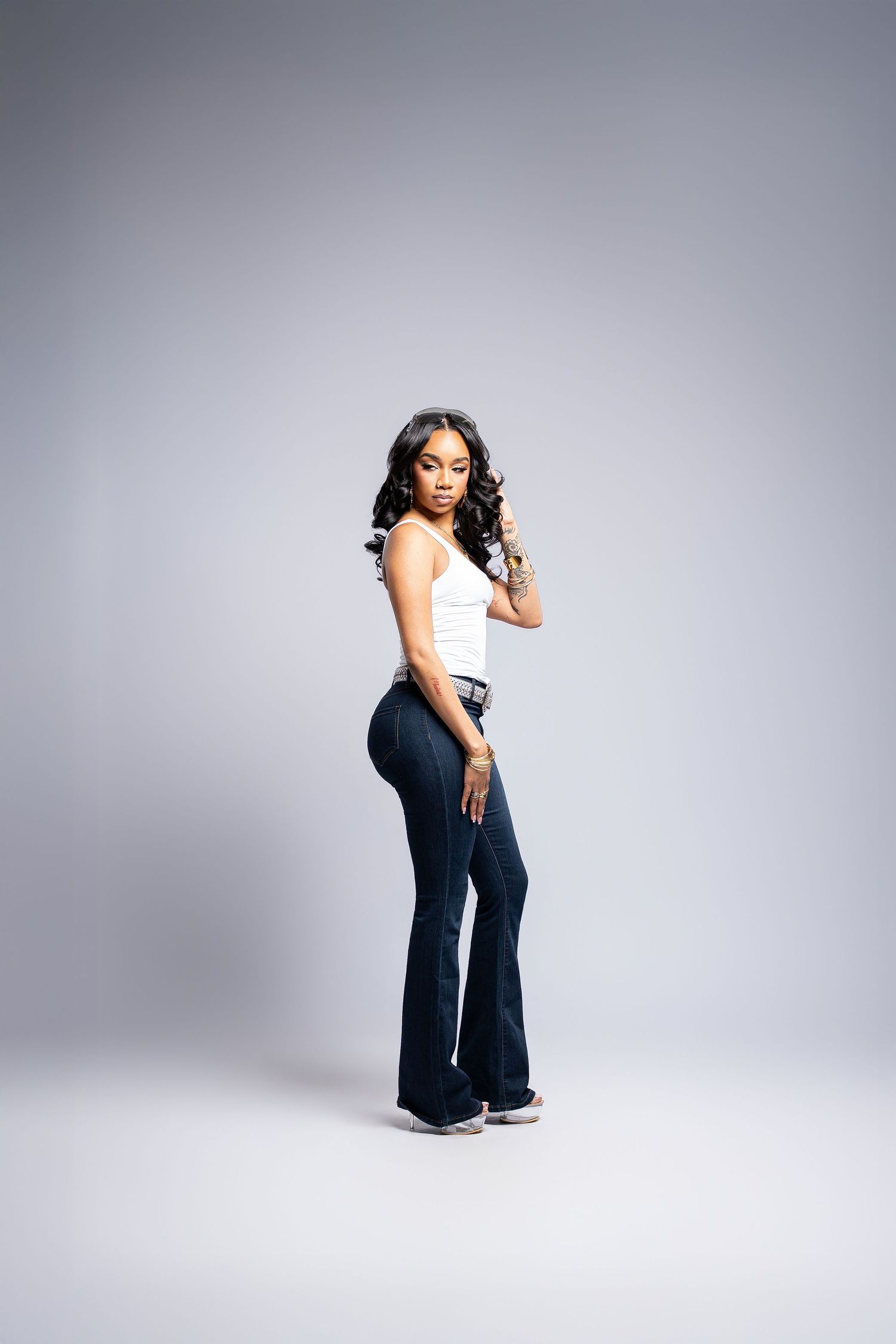 A figure poses against a gray studio backdrop in a stylish navy jumpsuit showing different angles and poses.