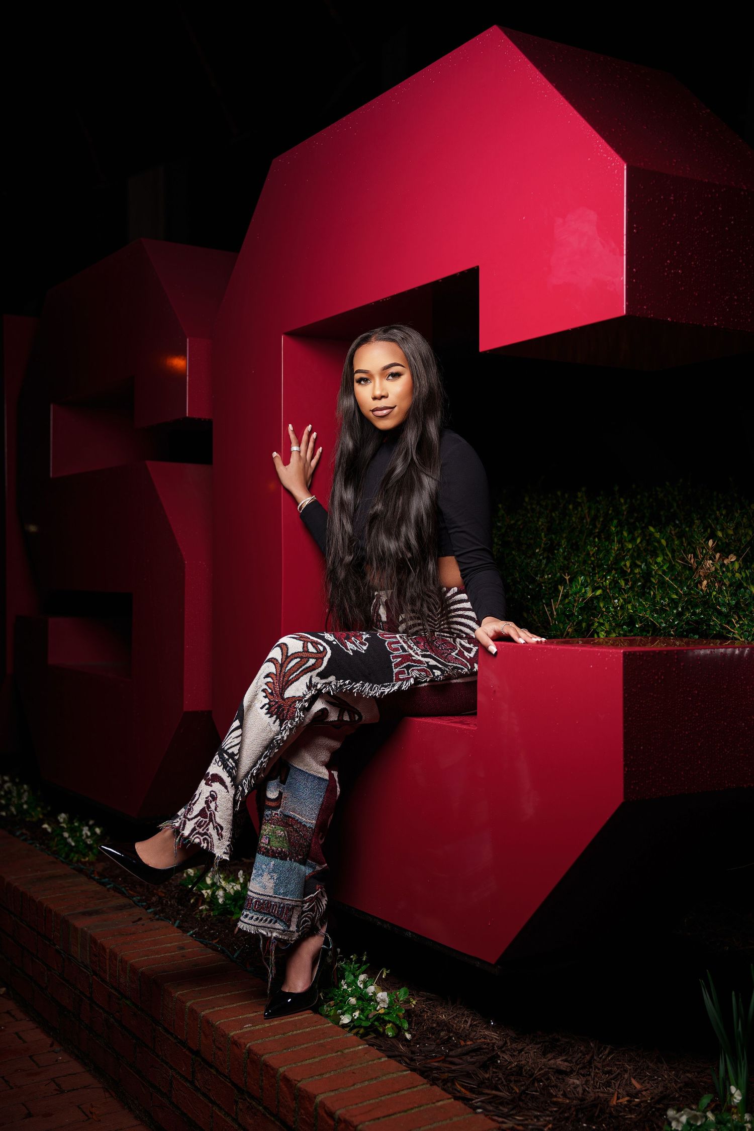 A series of photos against a vibrant red architectural wall at night showing dynamic poses in stylish clothing.