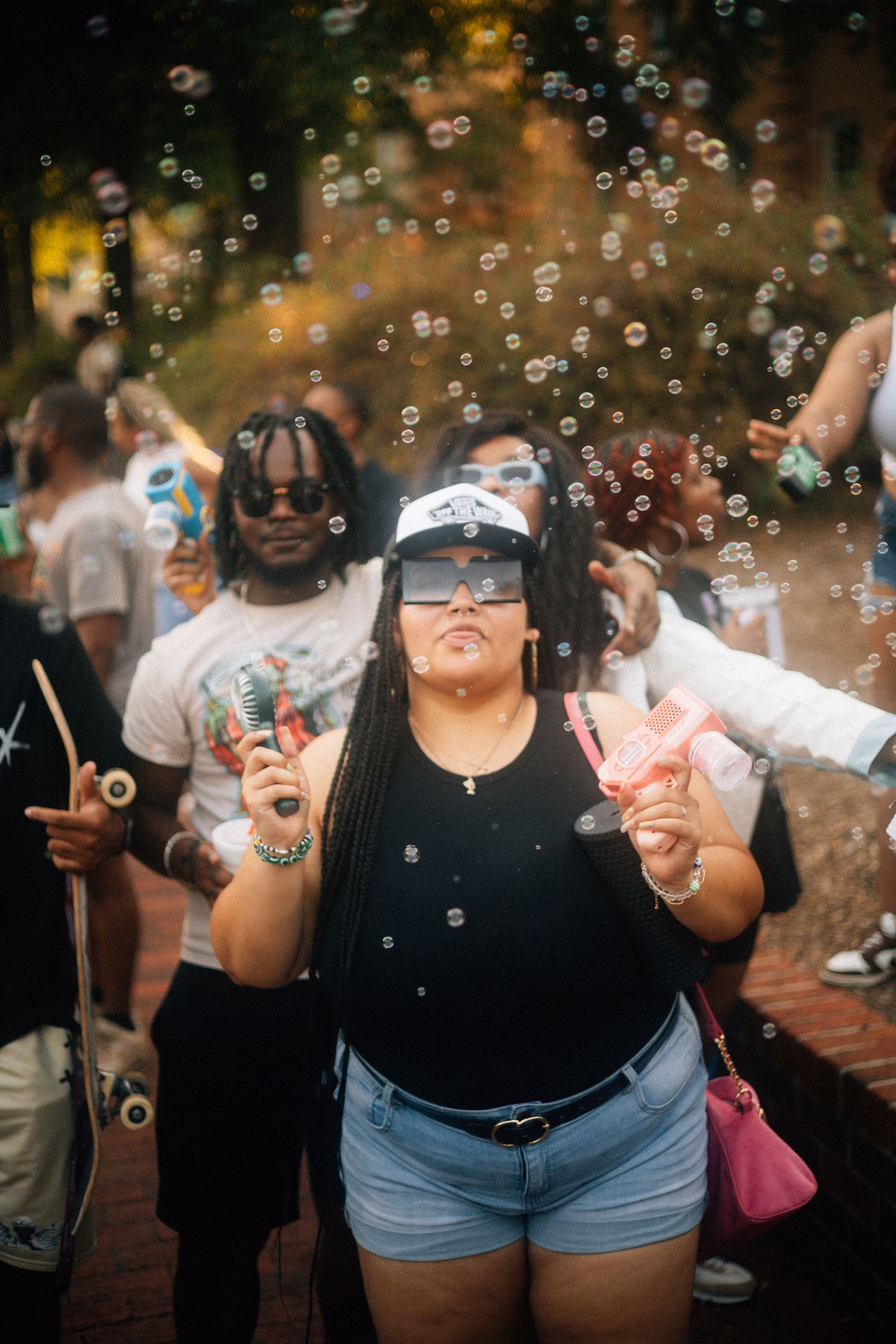 People enjoying summer festivities with soap bubbles floating in the air during an outdoor gathering.  USC Hip Hop Wednesday