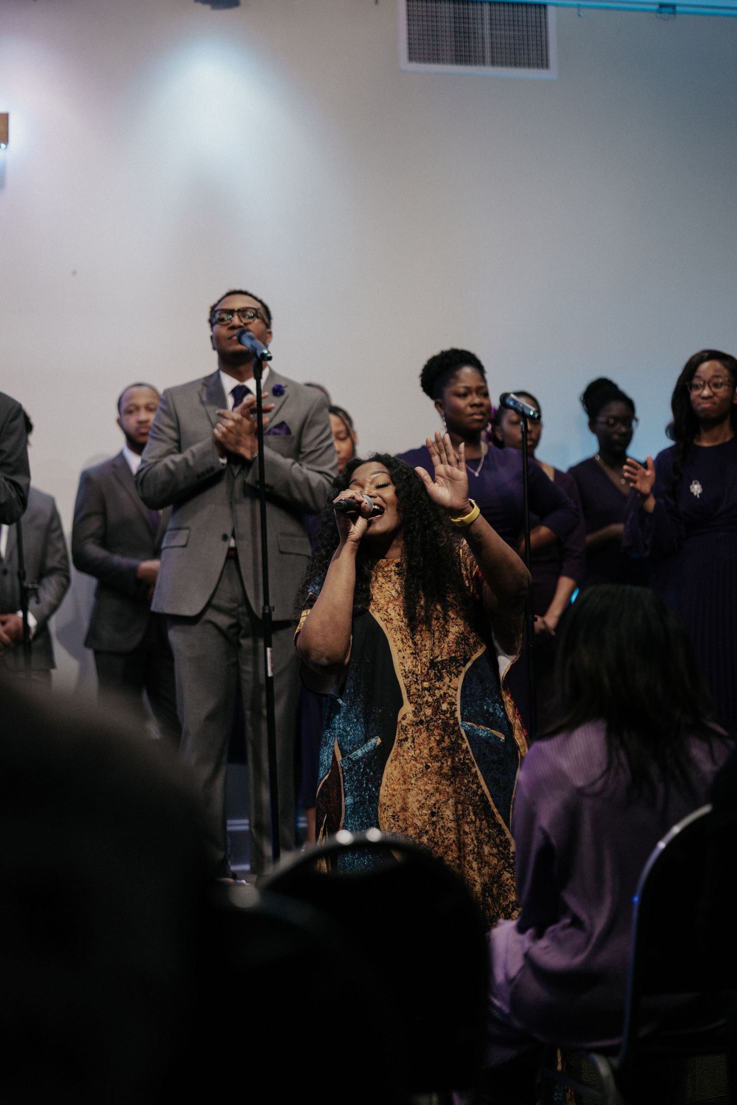 A congregation worships together with raised hands during an emotional church service.