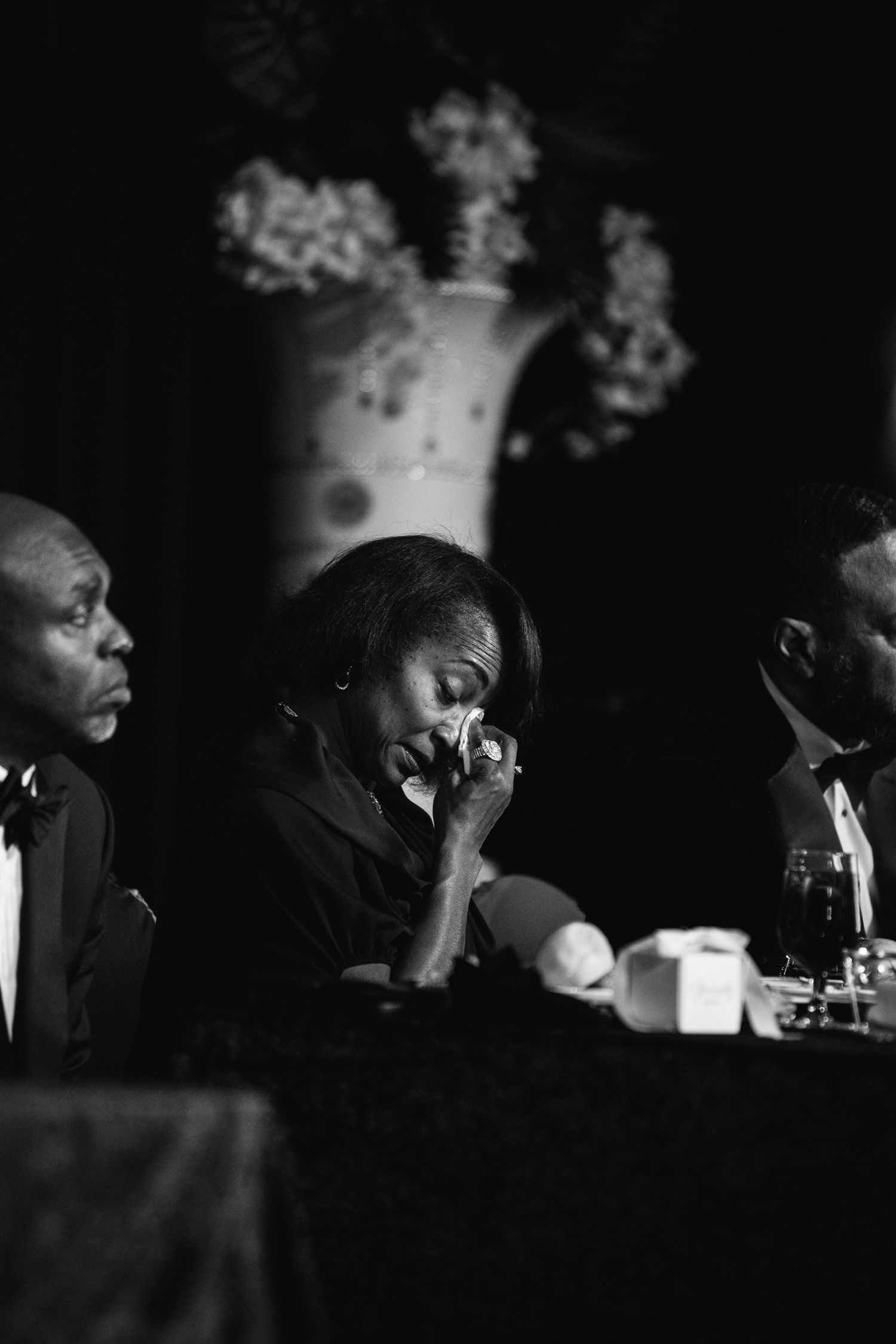 A black and white photograph shows musicians performing in a dimly lit venue with dramatic lighting.