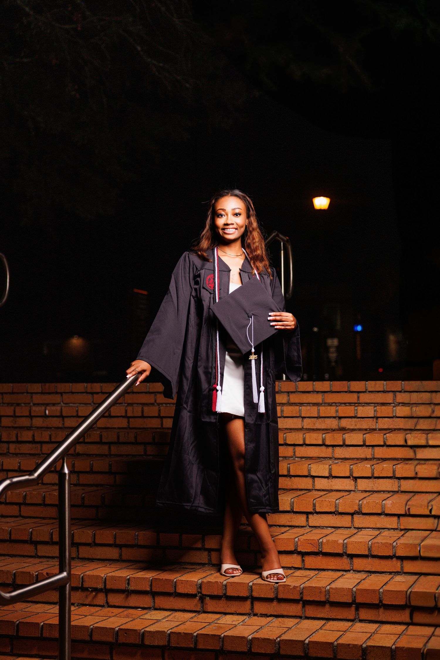 Graduate sitting on brick steps during evening graduation photo session.