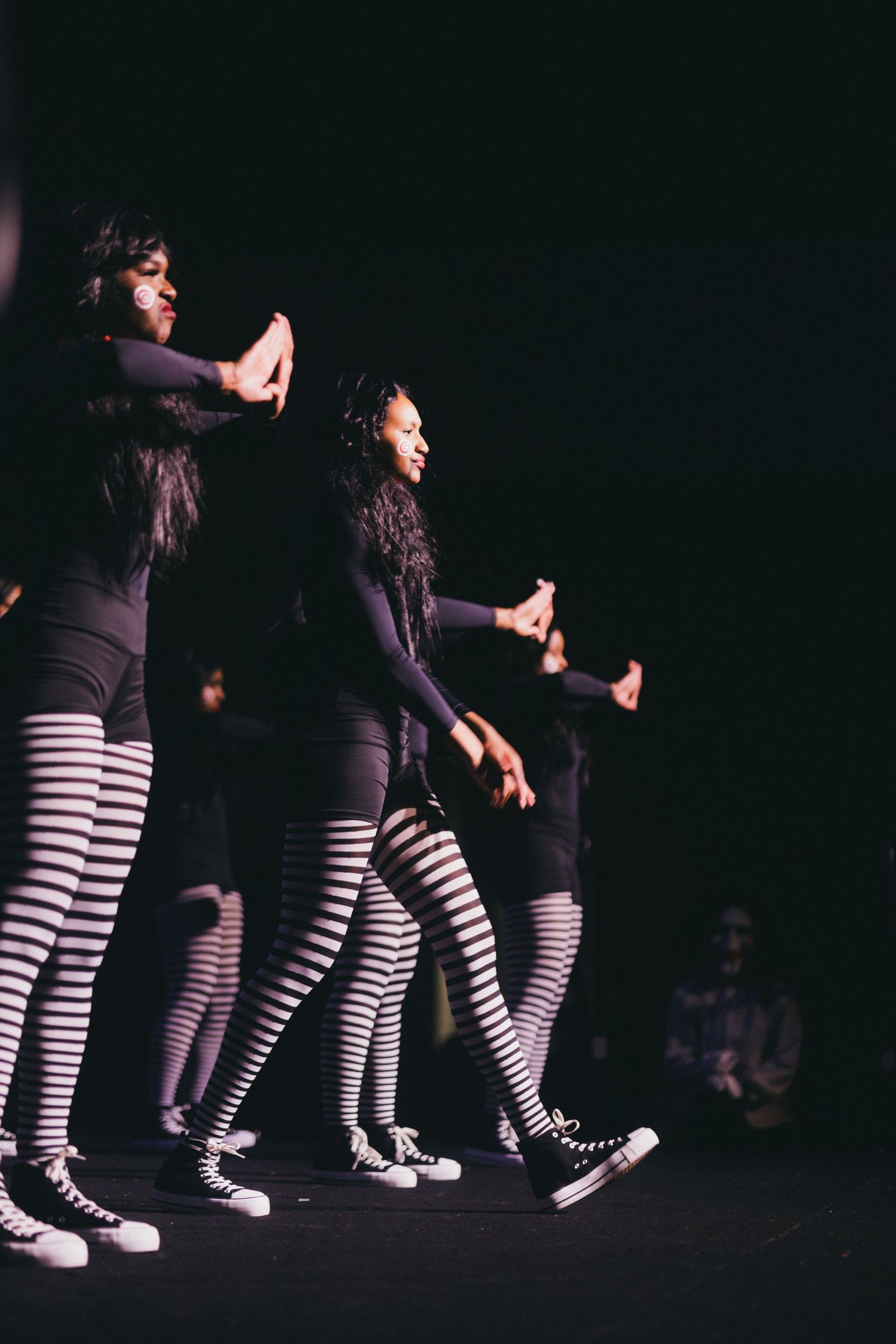 deltas perform in matching black tops and striped leggings on a dark stage.