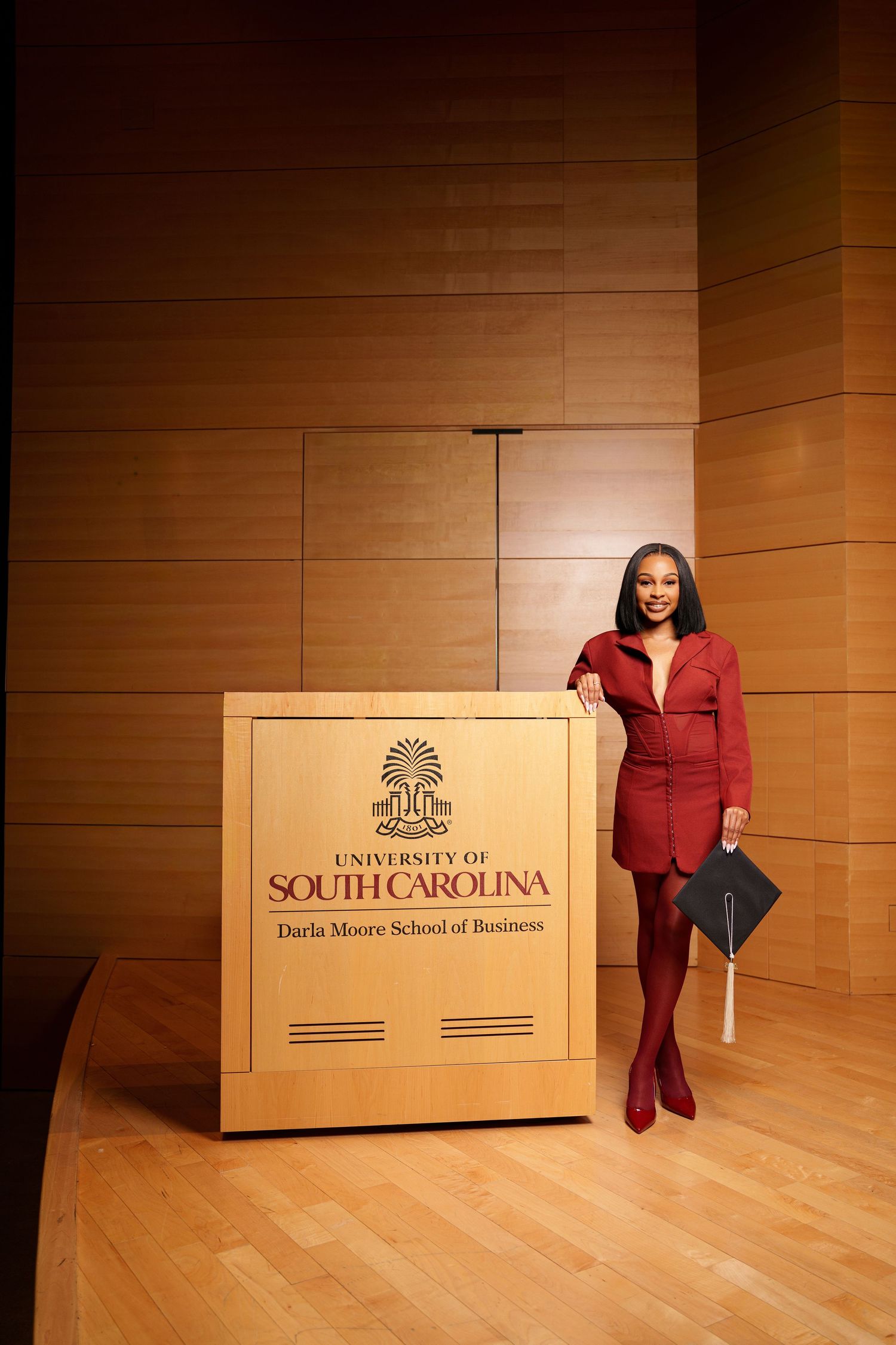 Graduate poses at University of South Carolina Darla Moore School of Business podium.
