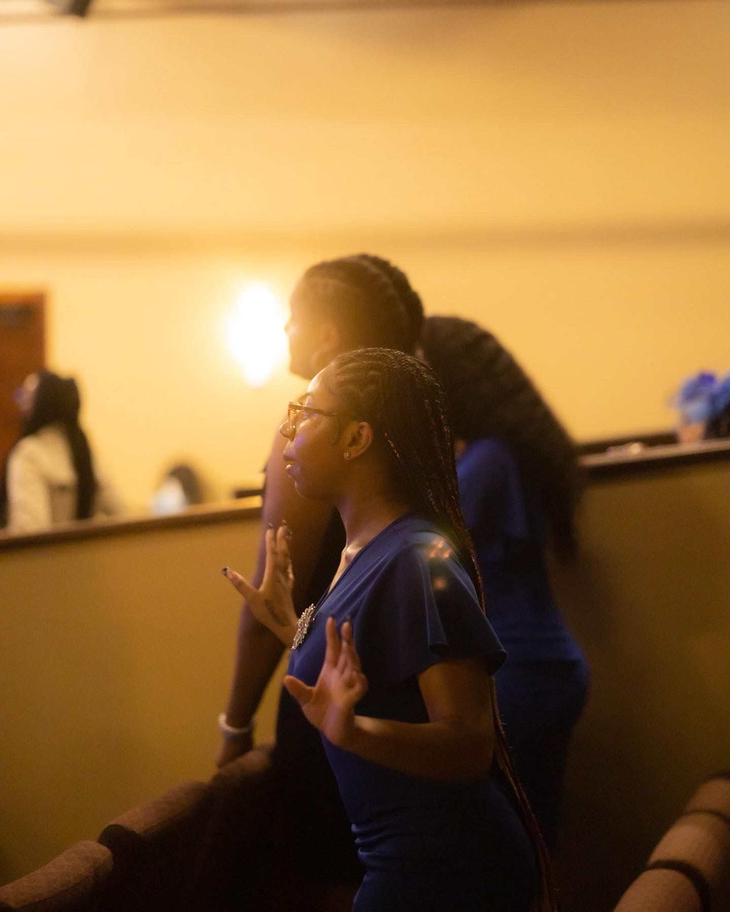 Gospel choir members performing in low warm lighting with passionate expressions.
