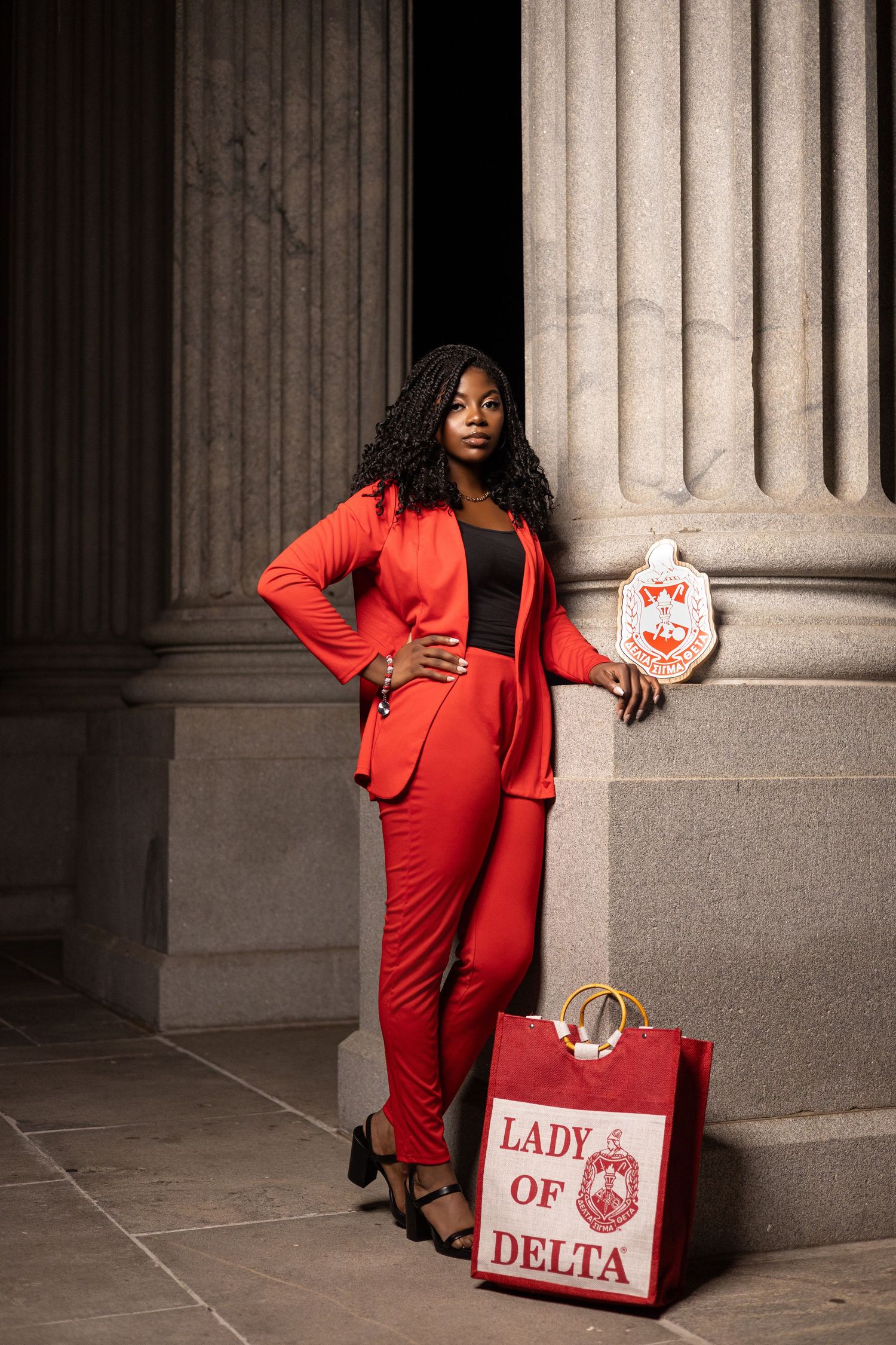 Professional photo of person in red suit with Delta-branded shopping bag by stone columns.