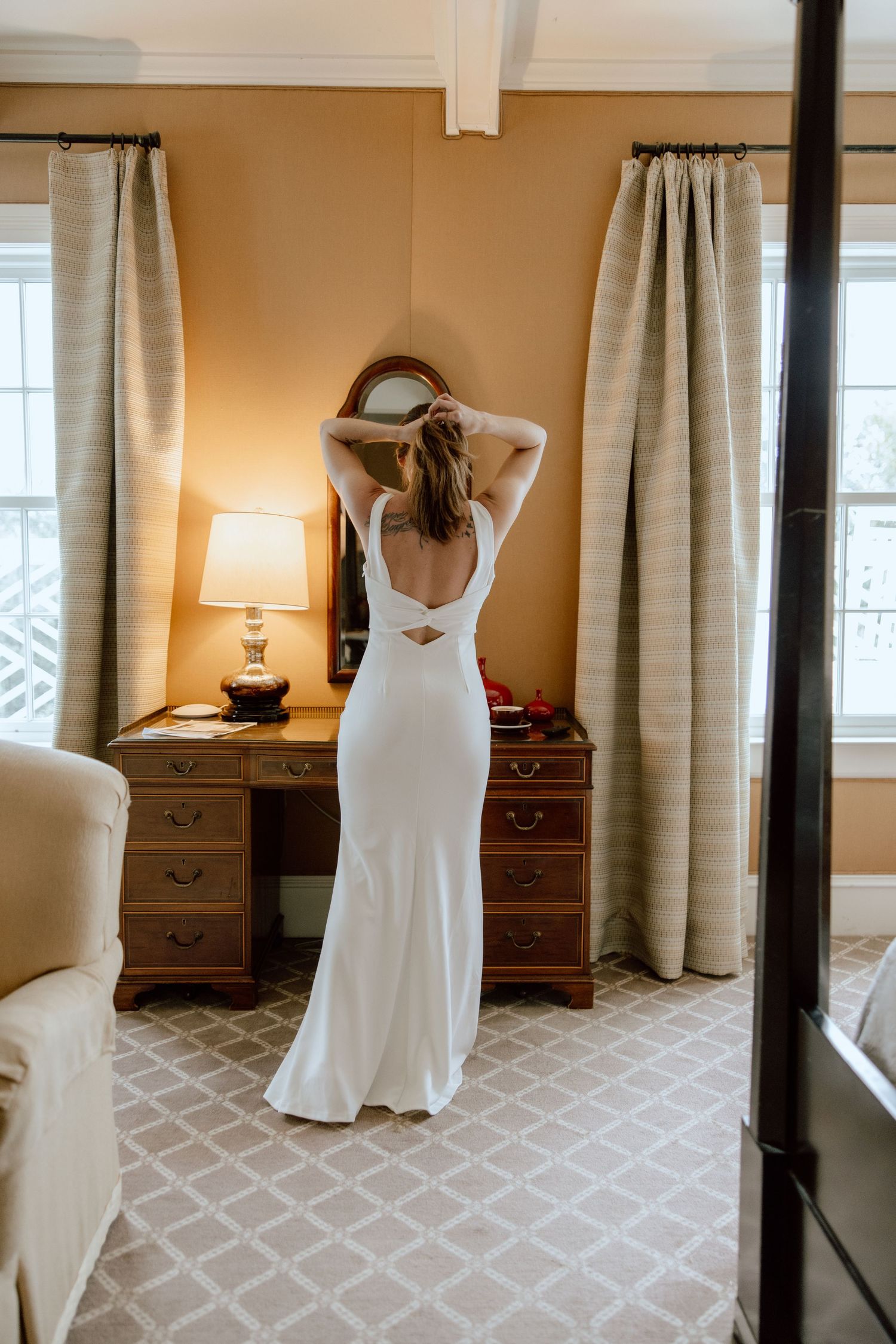 Three views of a white wedding dress displayed in a bedroom with beige walls, carpeting, and elegant curtains.