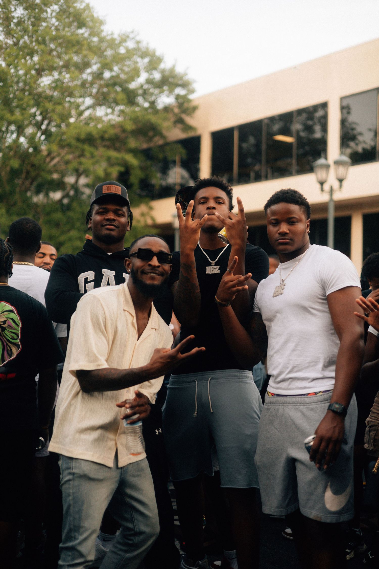 A group of young people posing informally together outdoors in front of a building making hand gestures. USC Hip Hop Wednesday