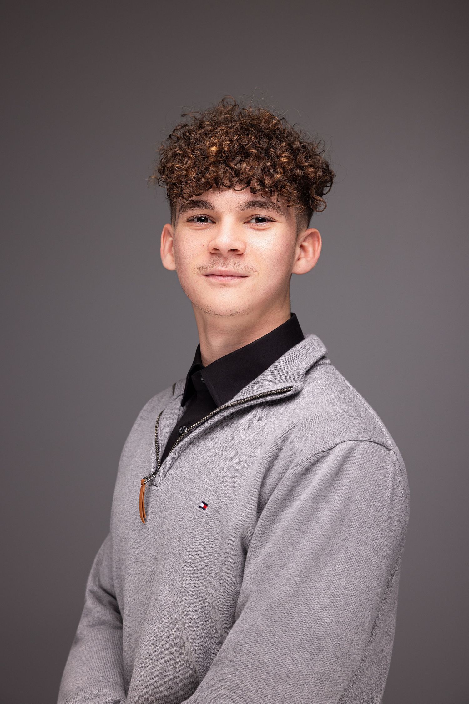 Studio portrait series showing different angles of a person wearing a grey quarter-zip pullover against a dark background.