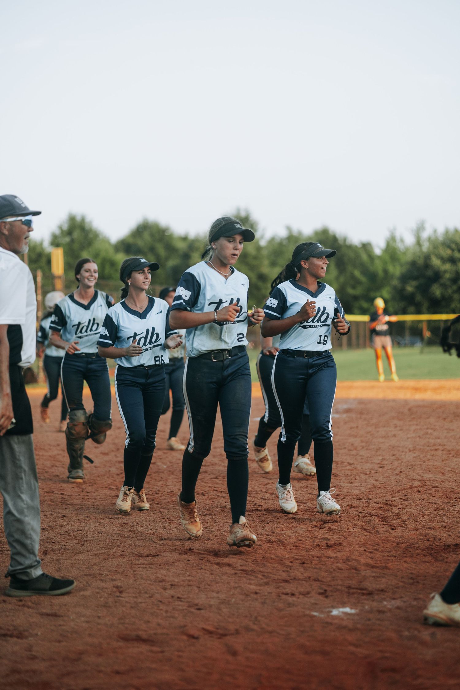 A softball team lines up on the infield dirt during a game.