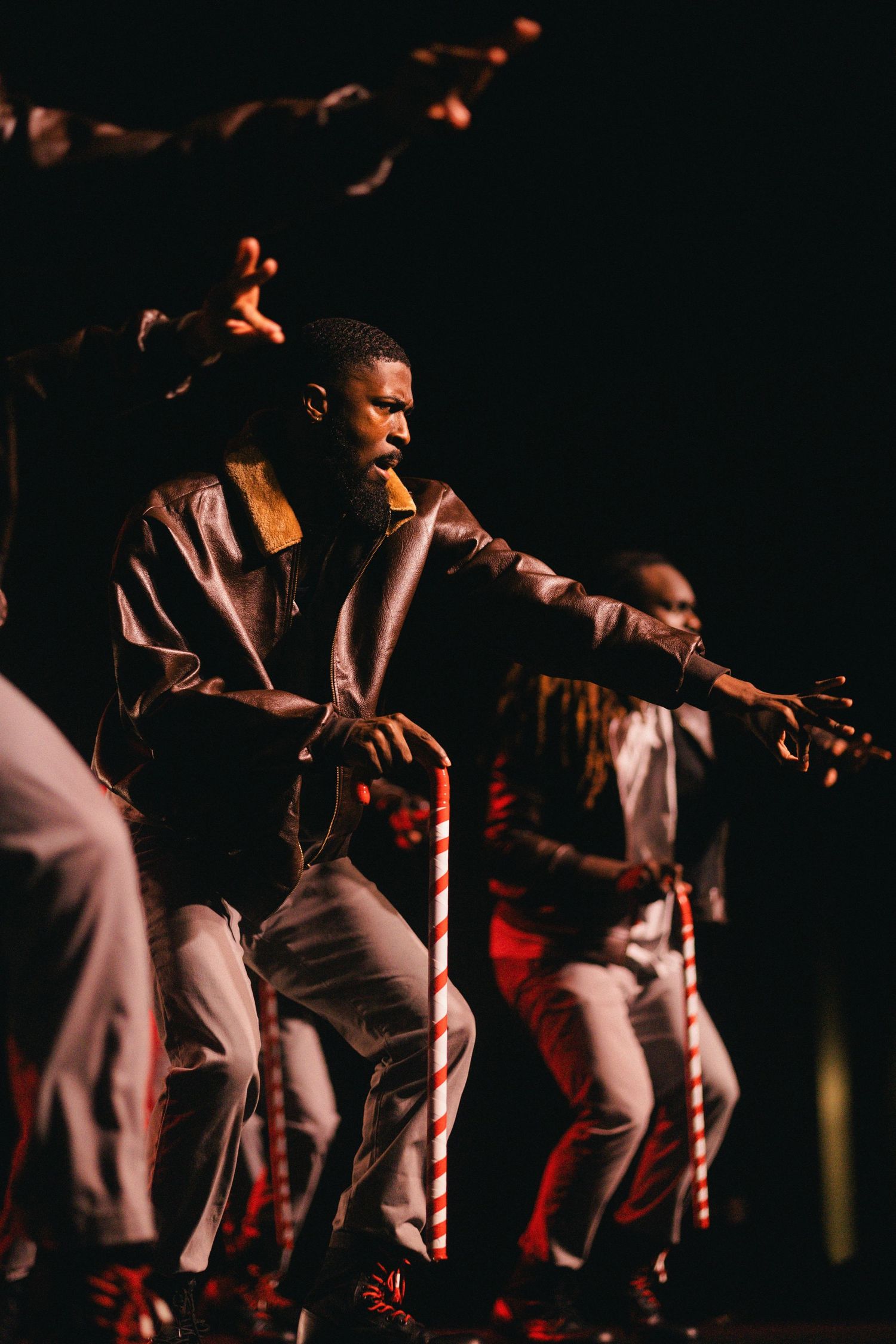 Nupes in white outfits perform energetically on a dimly lit stage with dramatic lighting effects.