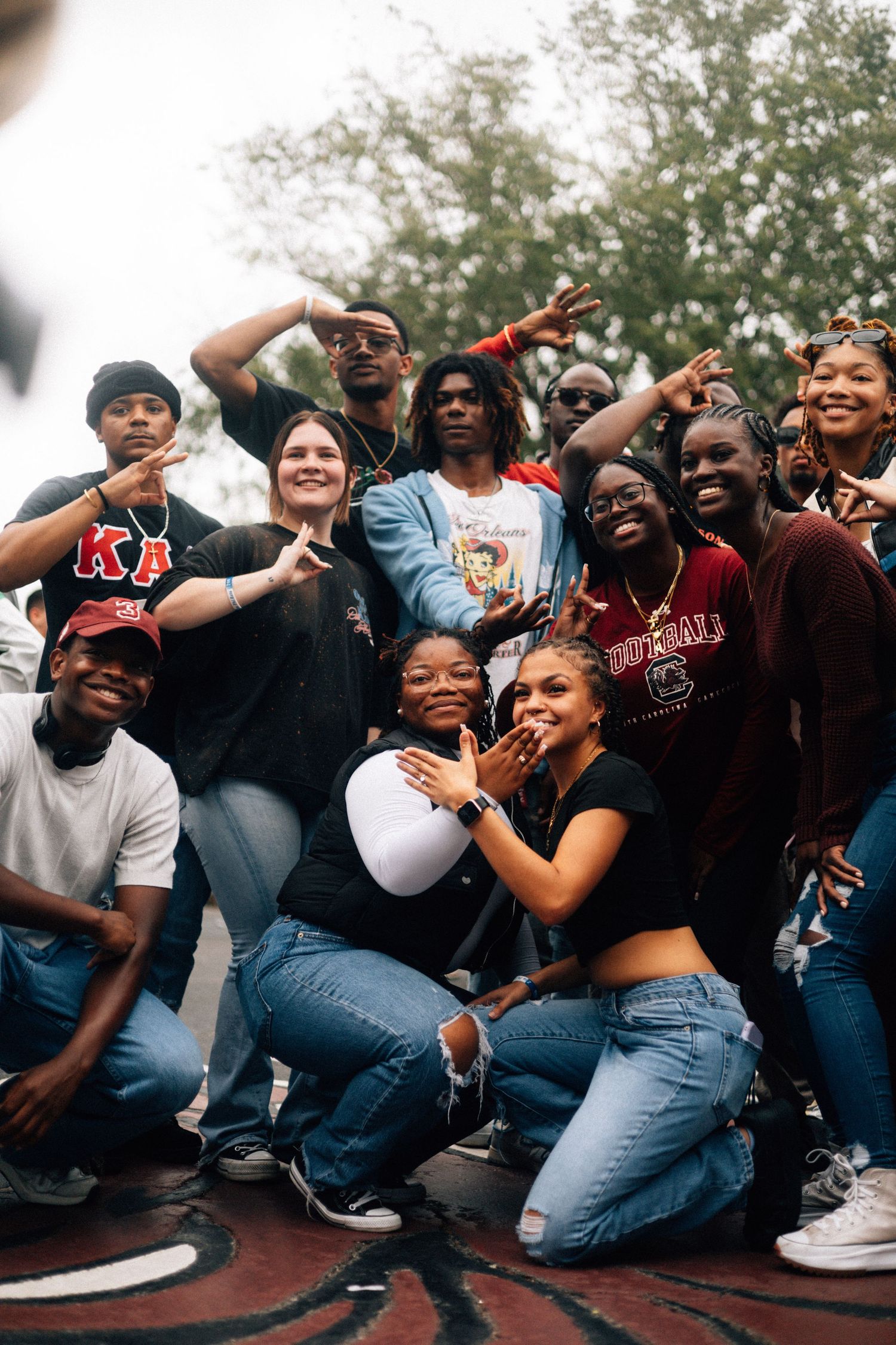 A cheerful group of friends in casual attire poses together outdoors, showing excitement and joy while taking a photo.  USC Hip Hop Wednesda