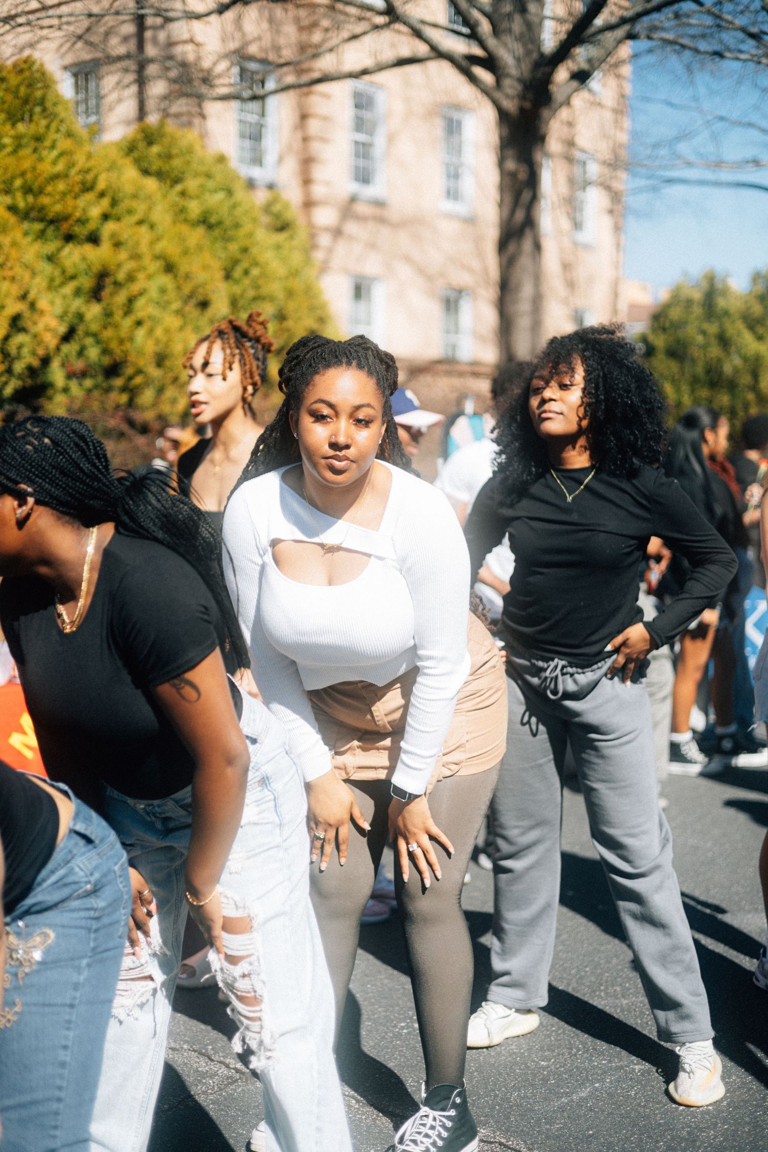 A group of zetas dancing on a sunny day near a brick building, with trees and foliage in the background.  USC Hip Hop Wednesday