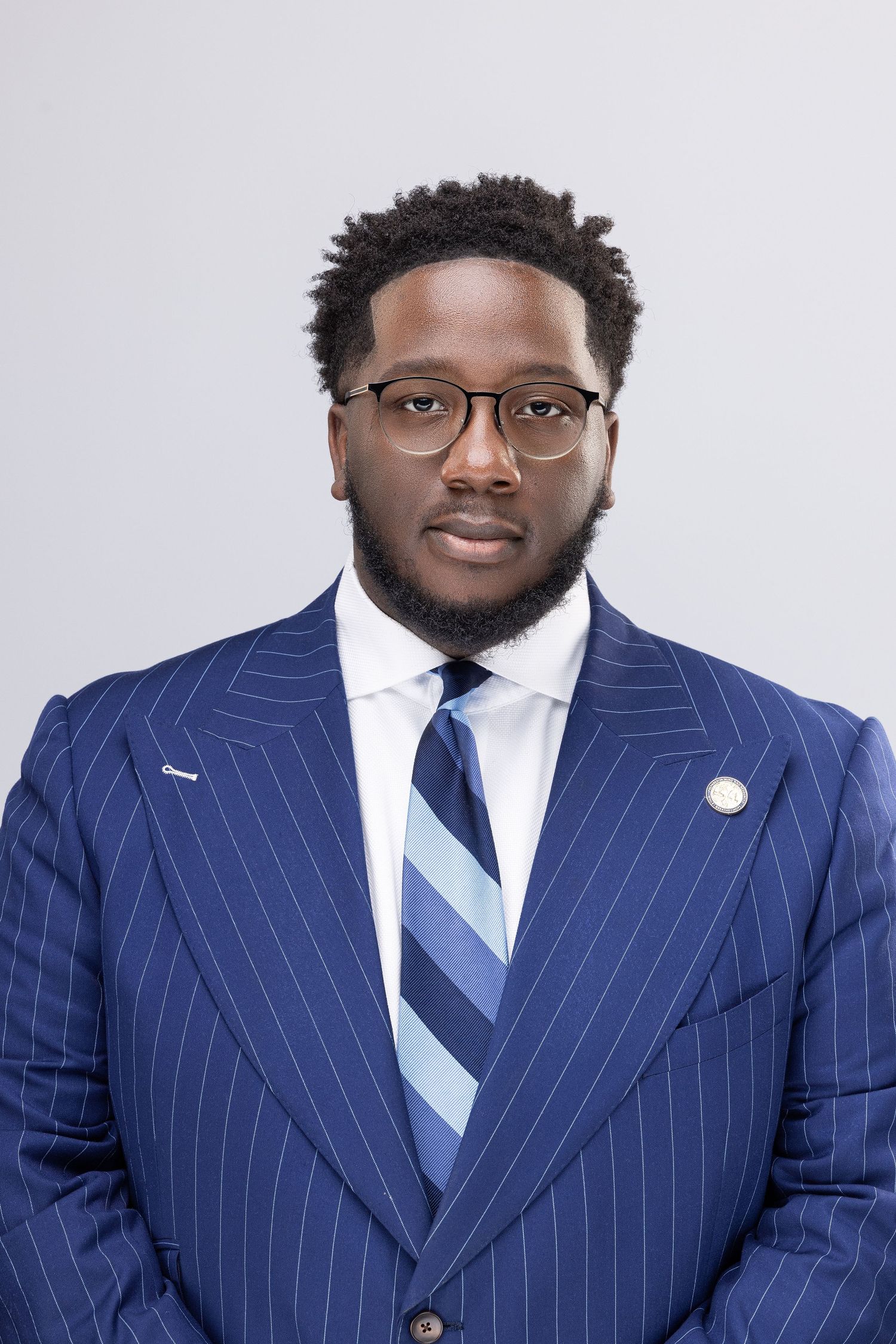 Professional headshot series showing a person in a navy pinstriped suit and light blue tie against a white background.