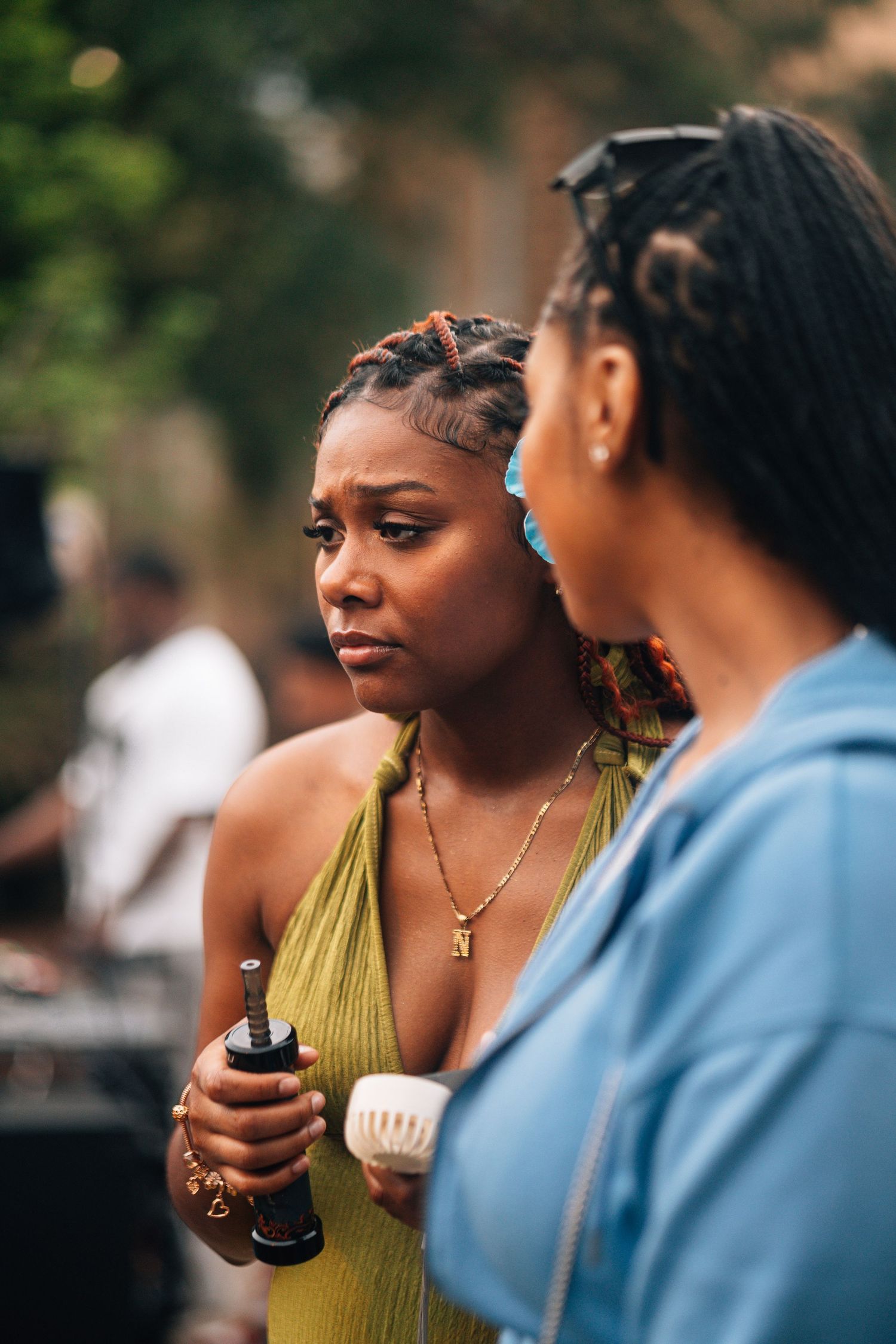 Two people engaged in an outdoor conversation while one holds what appears to be a beverage or small container.