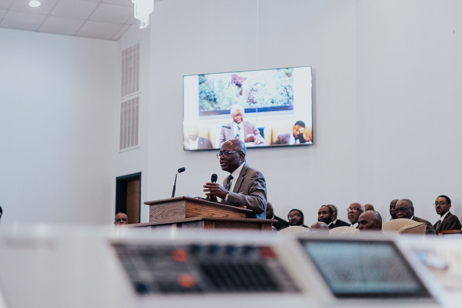 Business professionals gathered in a modern conference room with screens displaying presentations during a meeting.