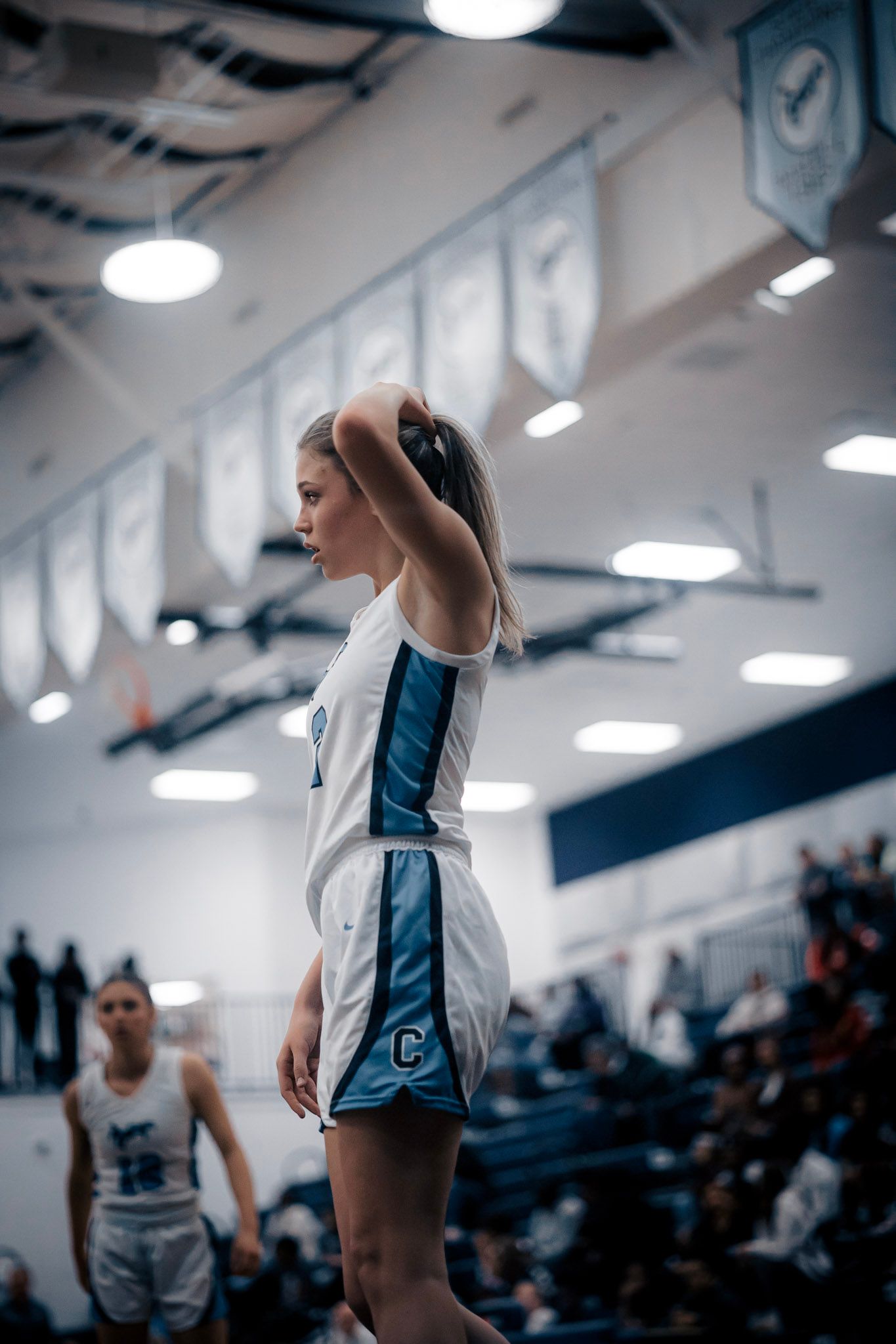 Basketball player in white and blue uniform shoots free throw in indoor gymnasium.