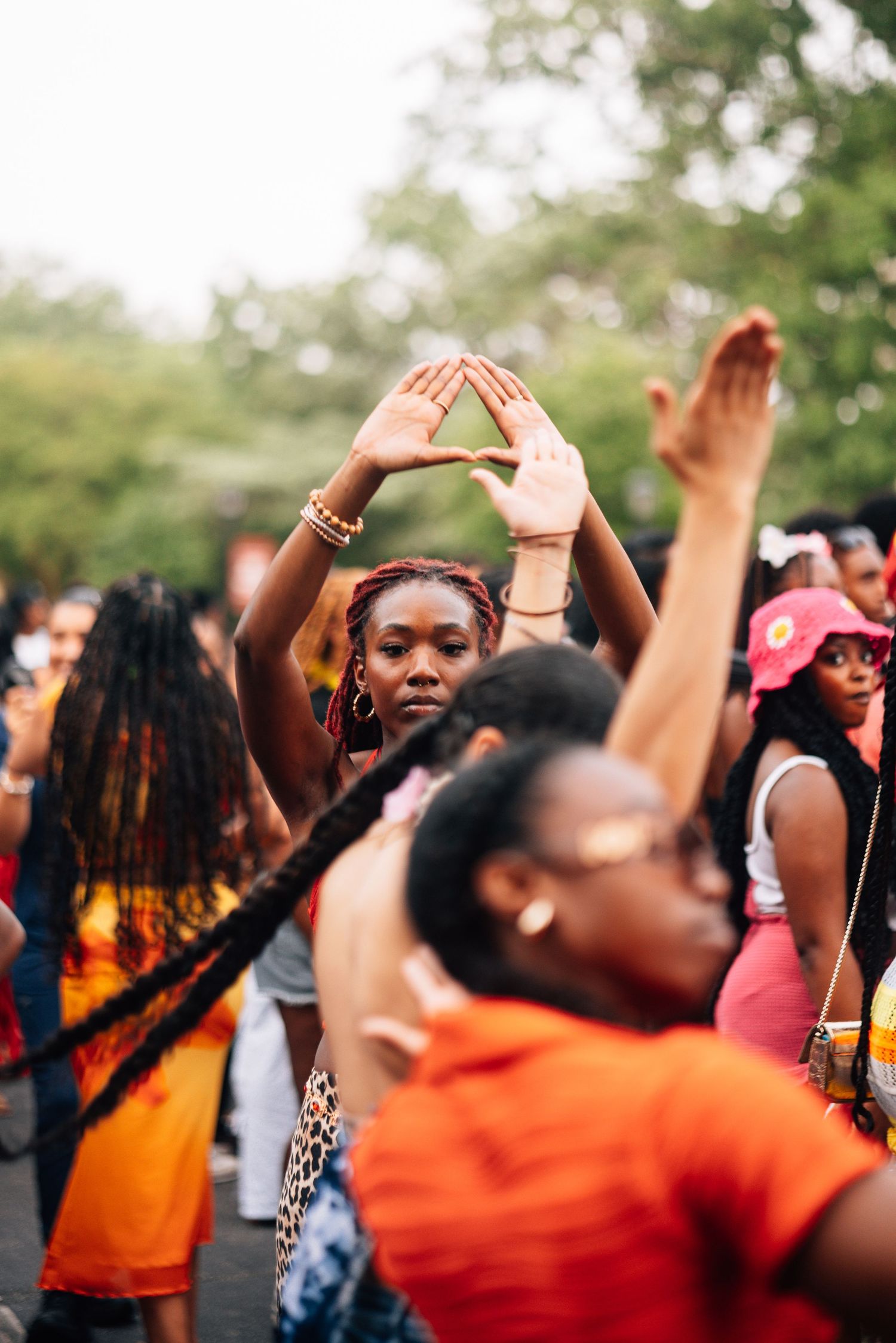 A crowd of people dancing and raising their hands during an outdoor festival on a sunny day.