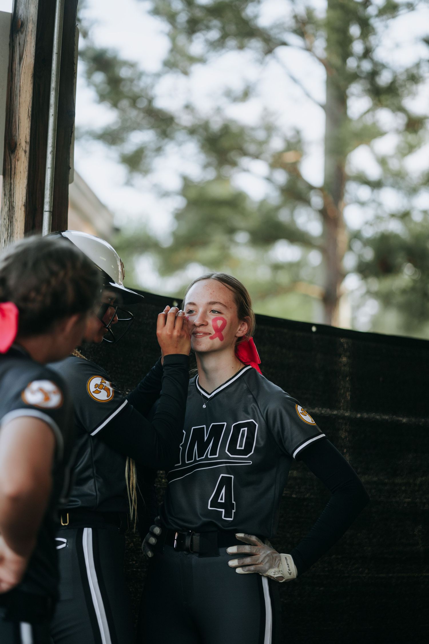 Irmo HS Softball teammates share a moment near dugout fence during game.
