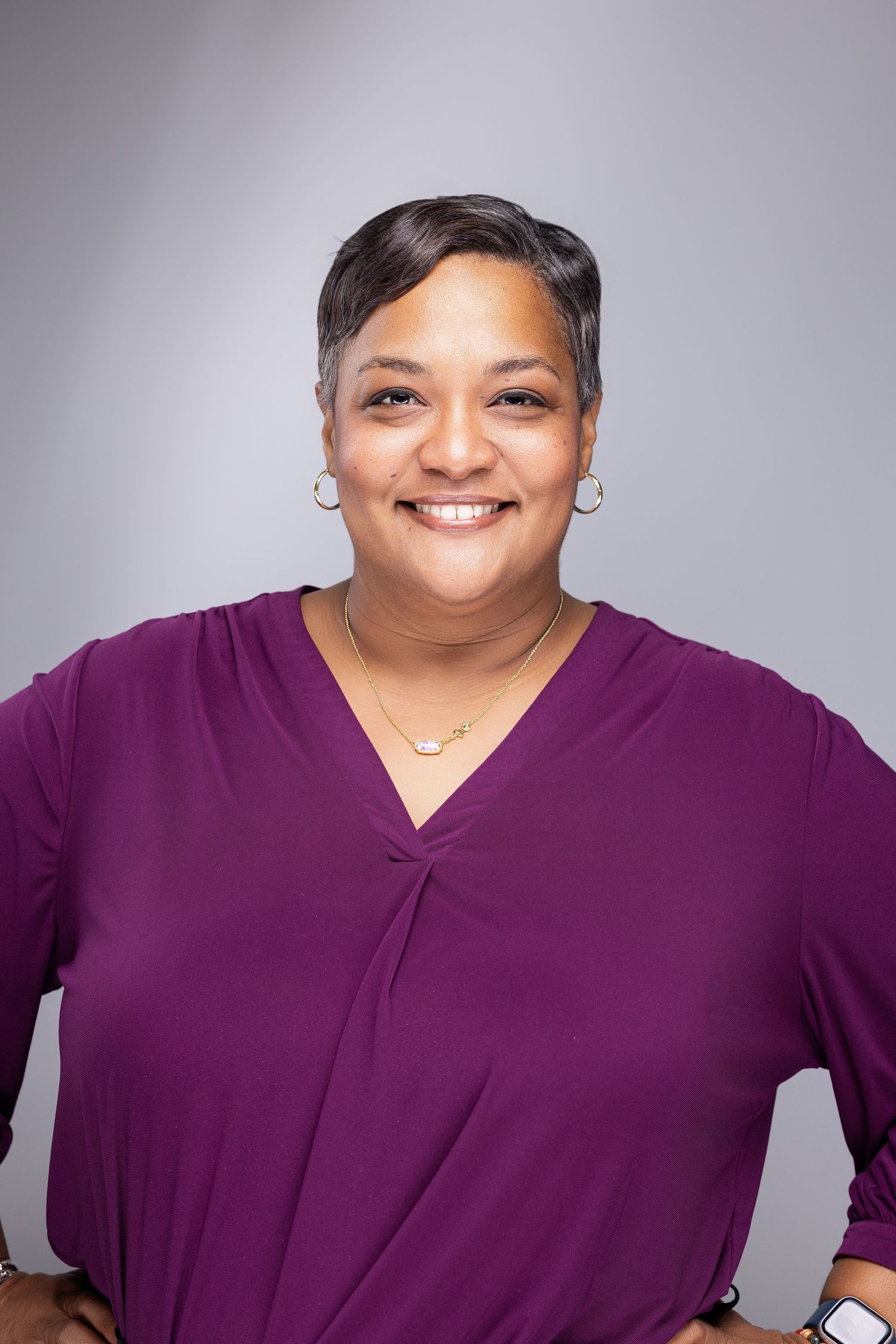 Professional headshot series showing expressions and poses in a purple top against a neutral gray studio background.