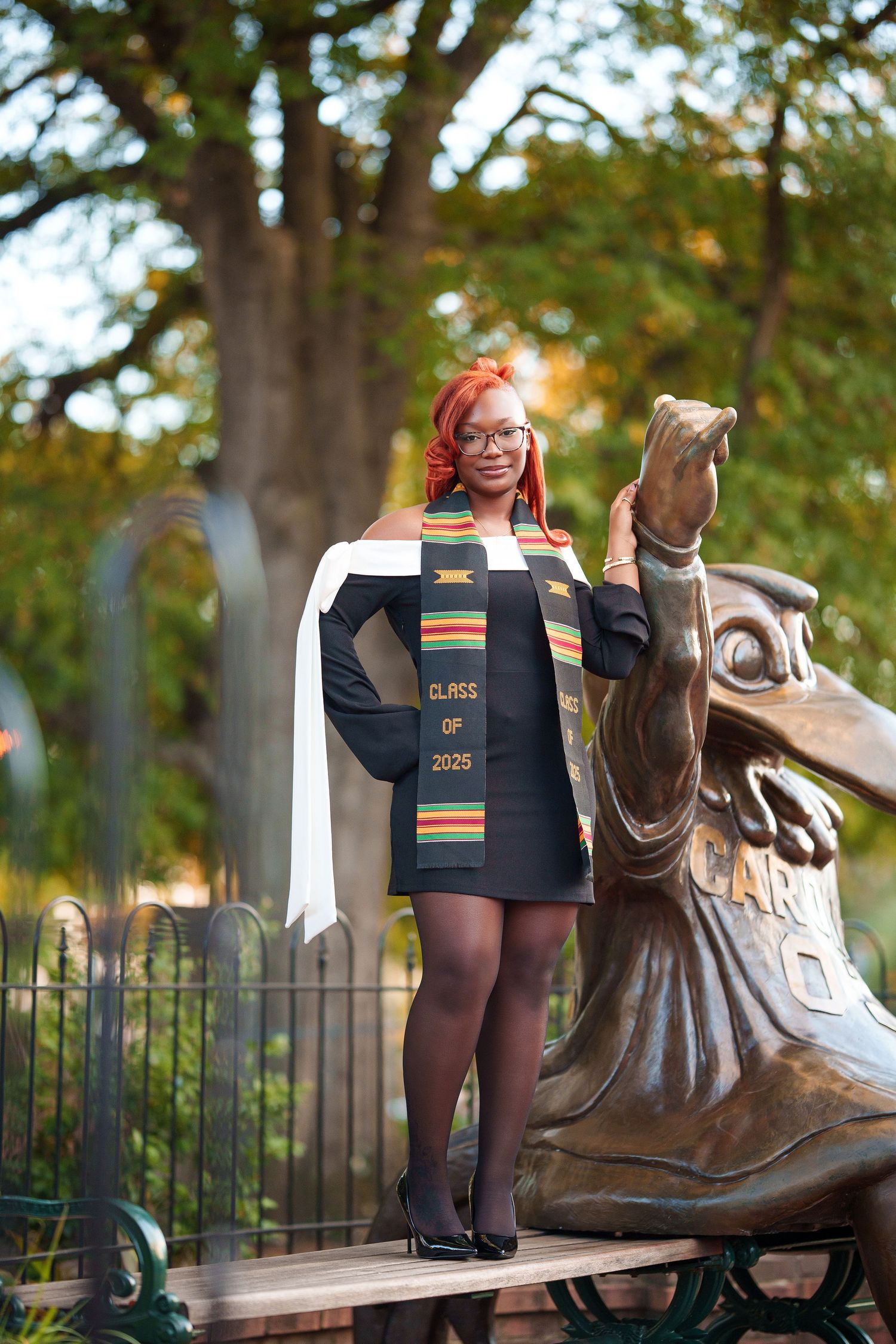 Rainbow striped socks shown in multiple poses next to a bronze sculpture on a park bench in autumn scenery.