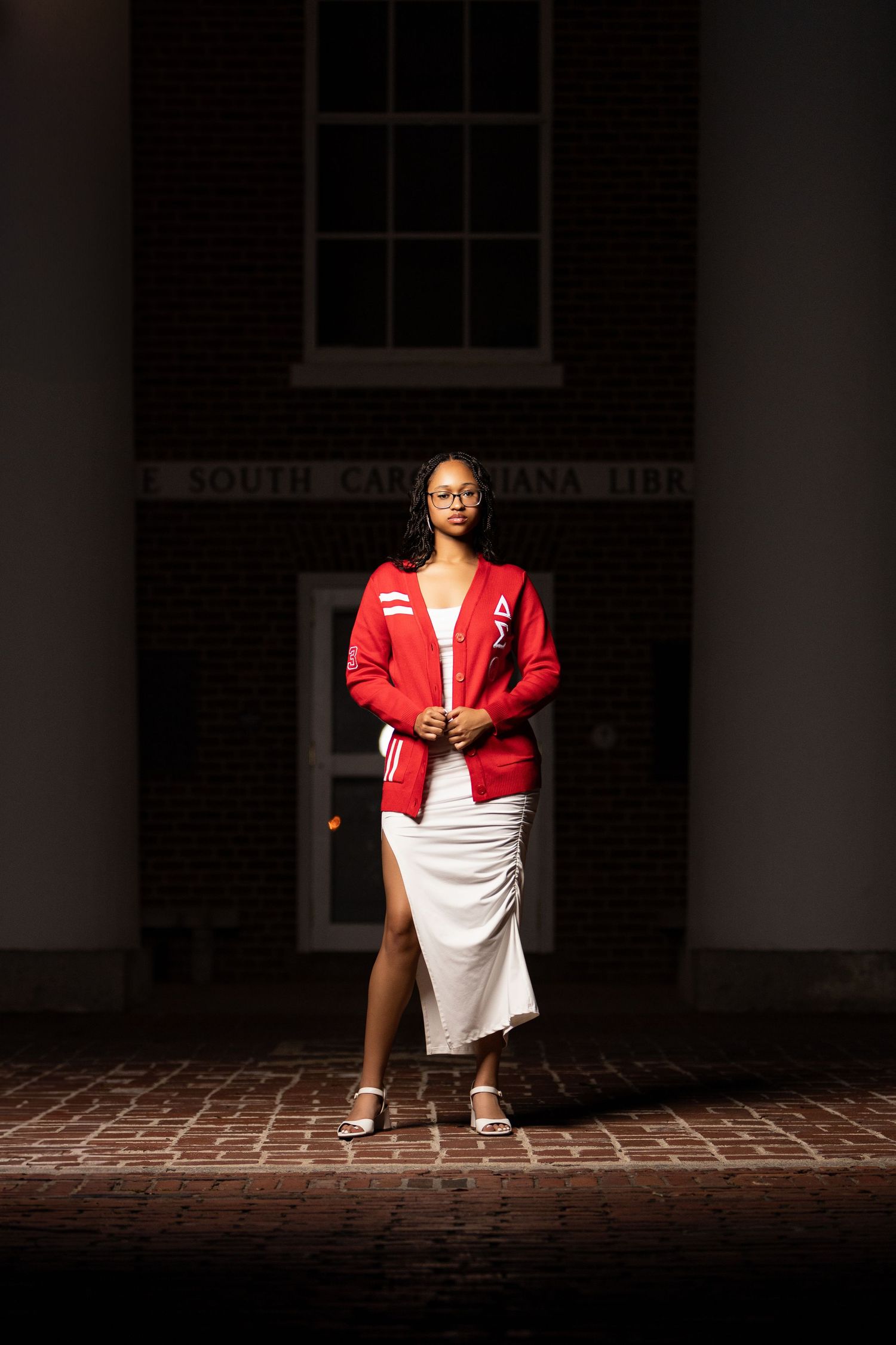 Dramatic contrast of red jacket and white dress on brick walkway at dusk.