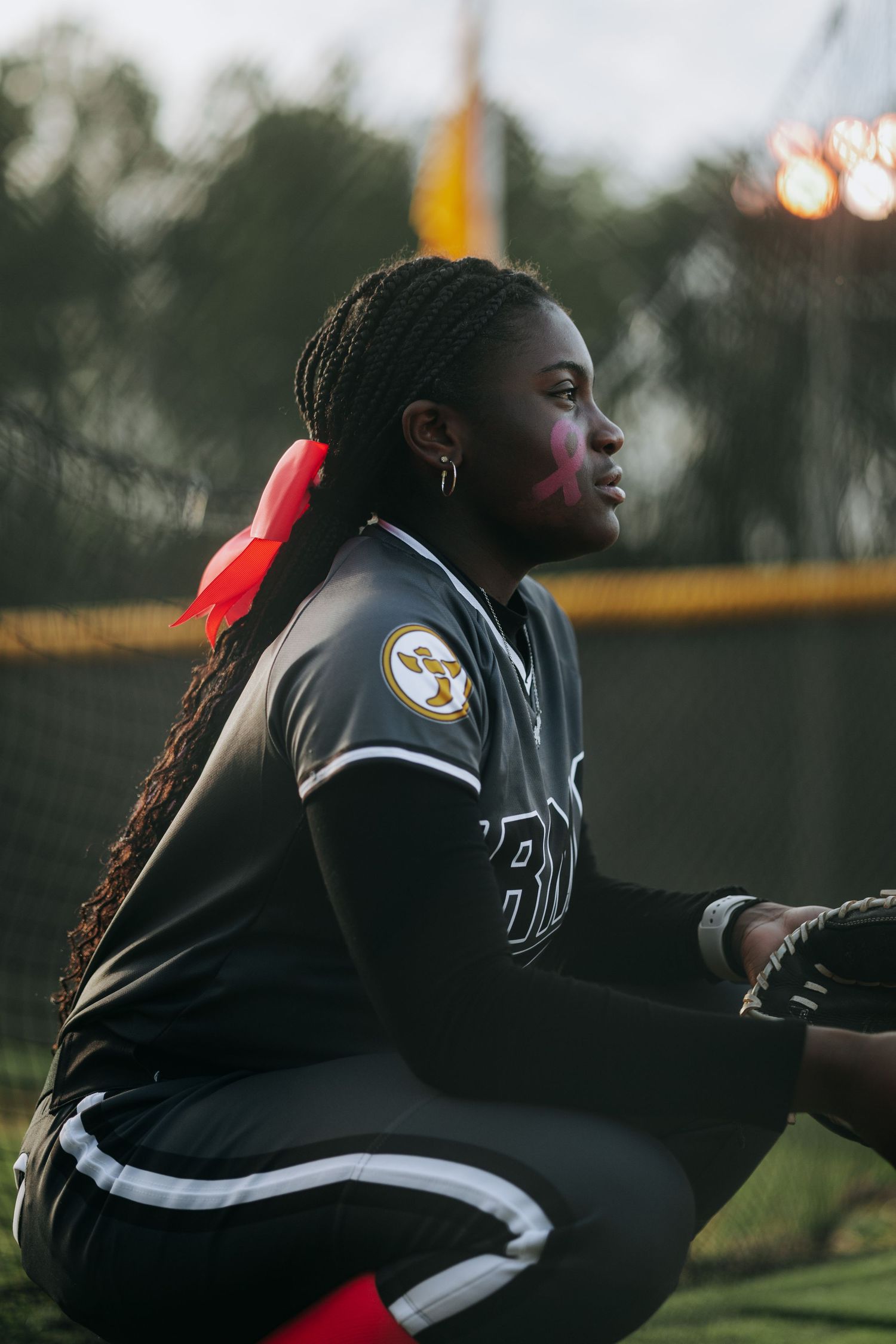 Irmo HS Softball player in dark uniform sits in dugout during game.