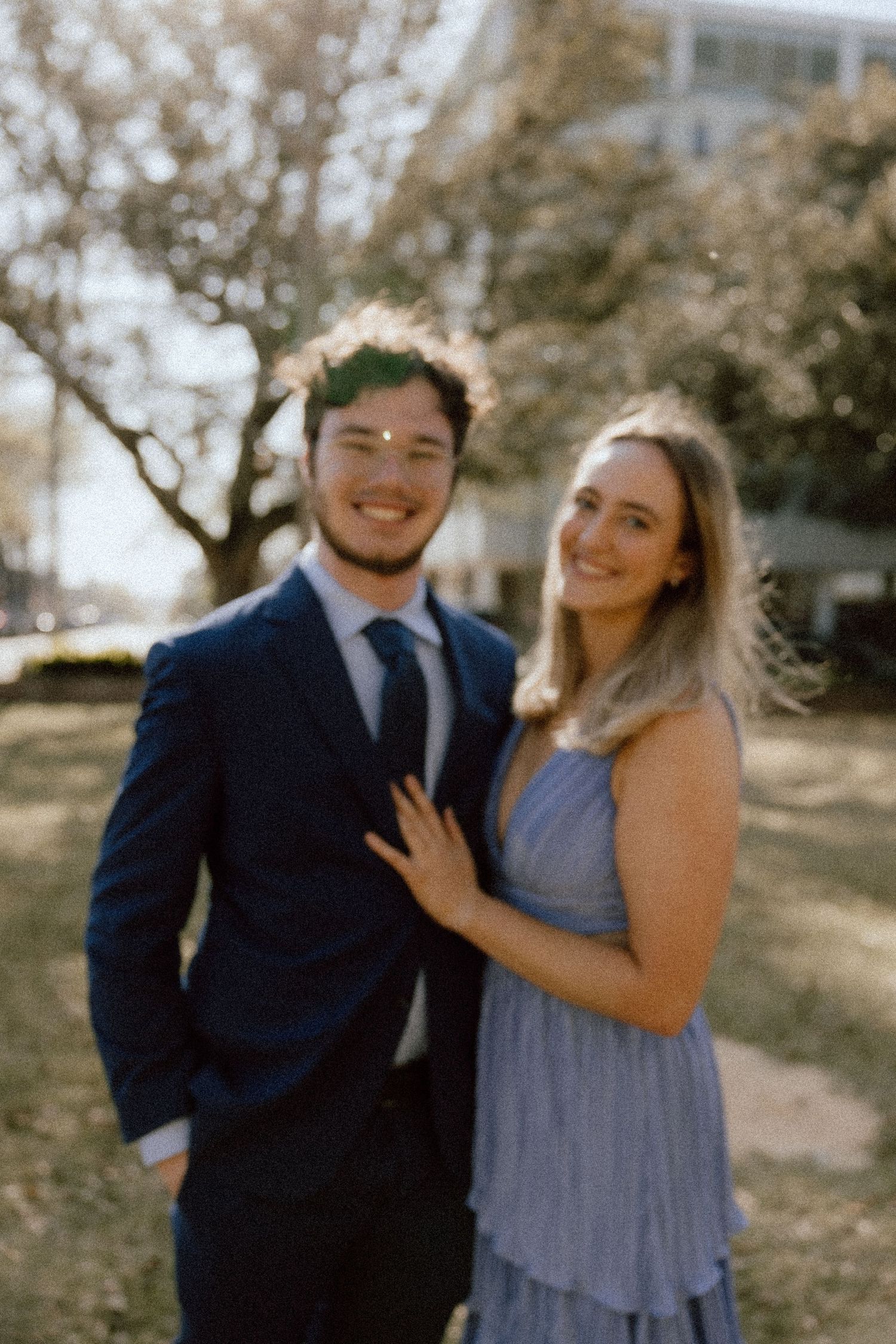 A couple shares joyful moments together outdoors in formal attire on a sunny day.