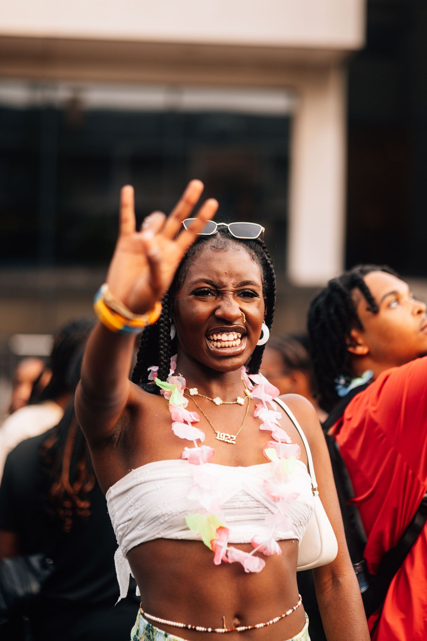 Joyful festival-goer in a white crop top flashes peace sign while celebrating at an outdoor event.