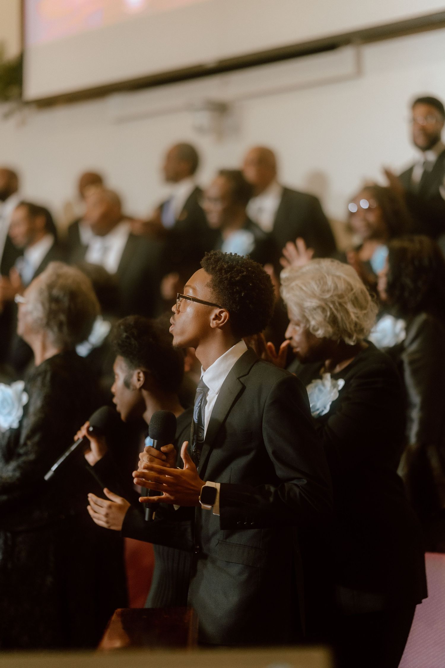 A crowd of formally dressed people standing in a row looking upward during what appears to be a ceremony or event.