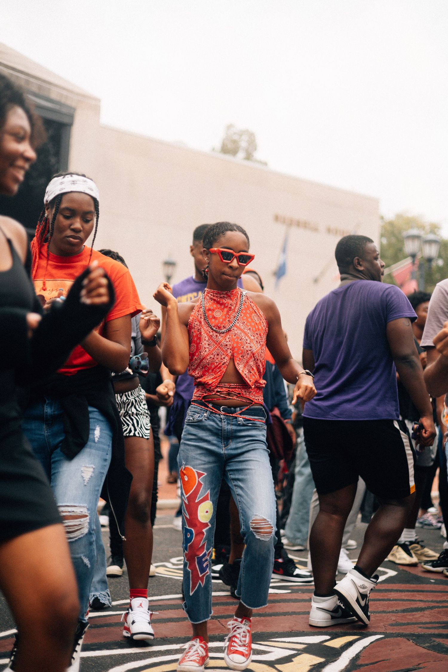 People dancing together during an outdoor gathering event on a paved area.
