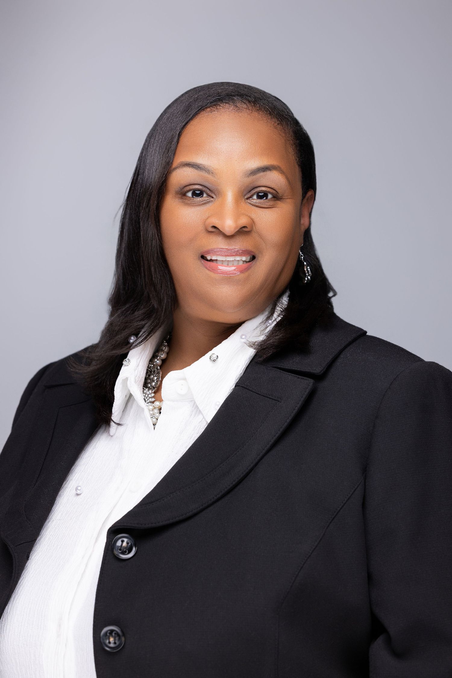 Professional headshot series showing a person in a black blazer and white shirt against a gray background.