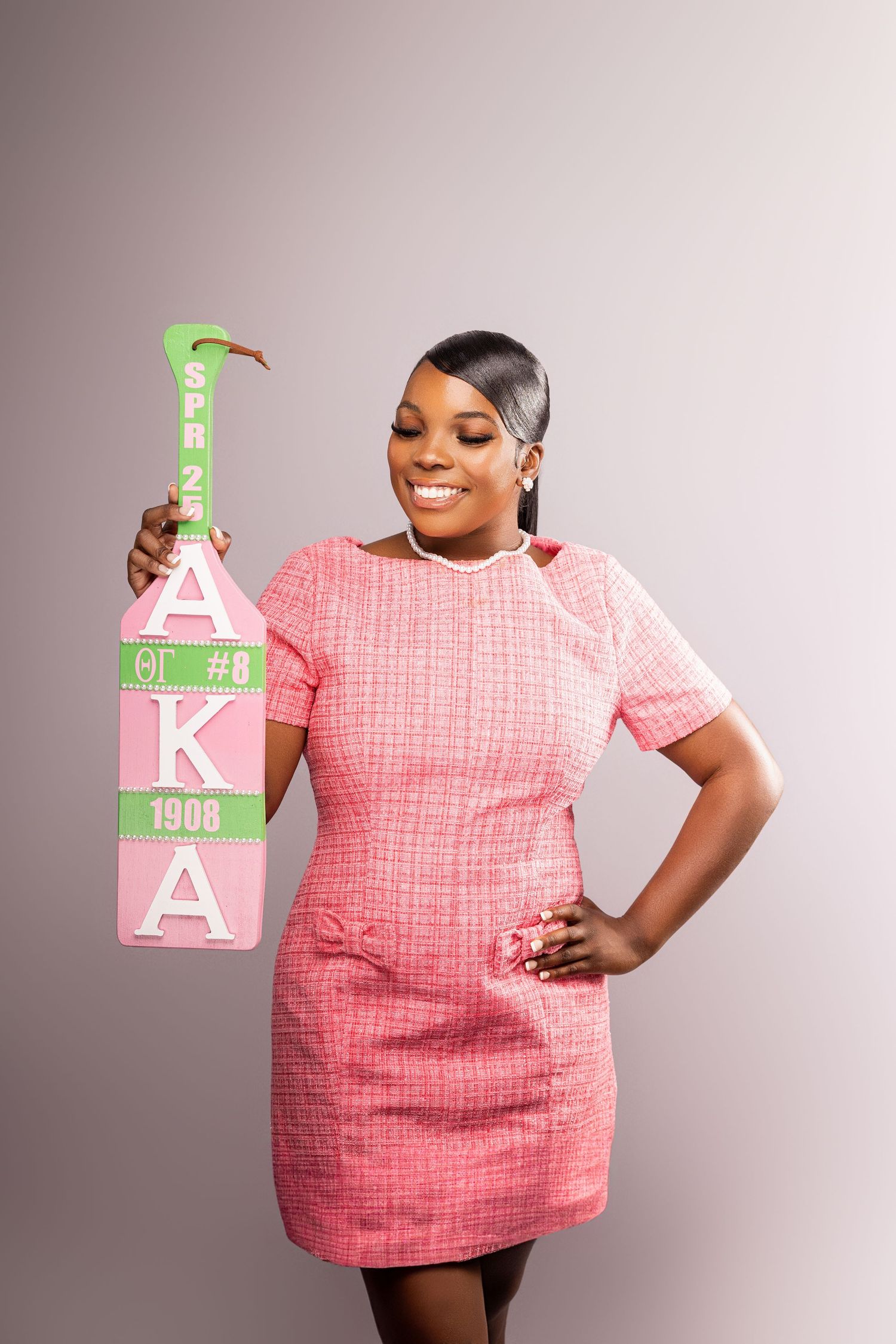 A person in a pink dress poses with decorative letter blocks in a studio photoshoot.