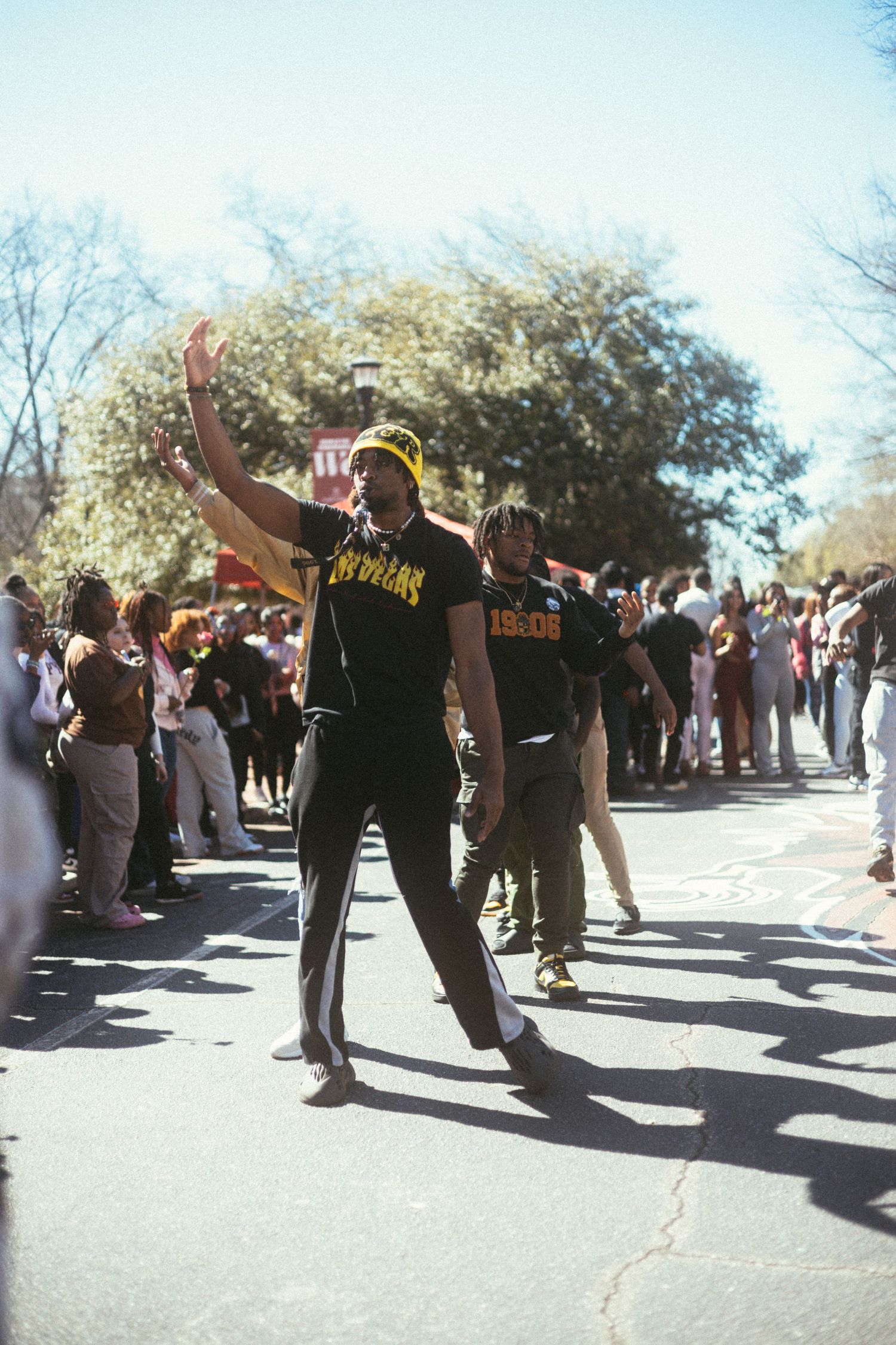 alphas dancing and celebrating at an outdoor gathering on a sunny day, with a crowd visible in the background.