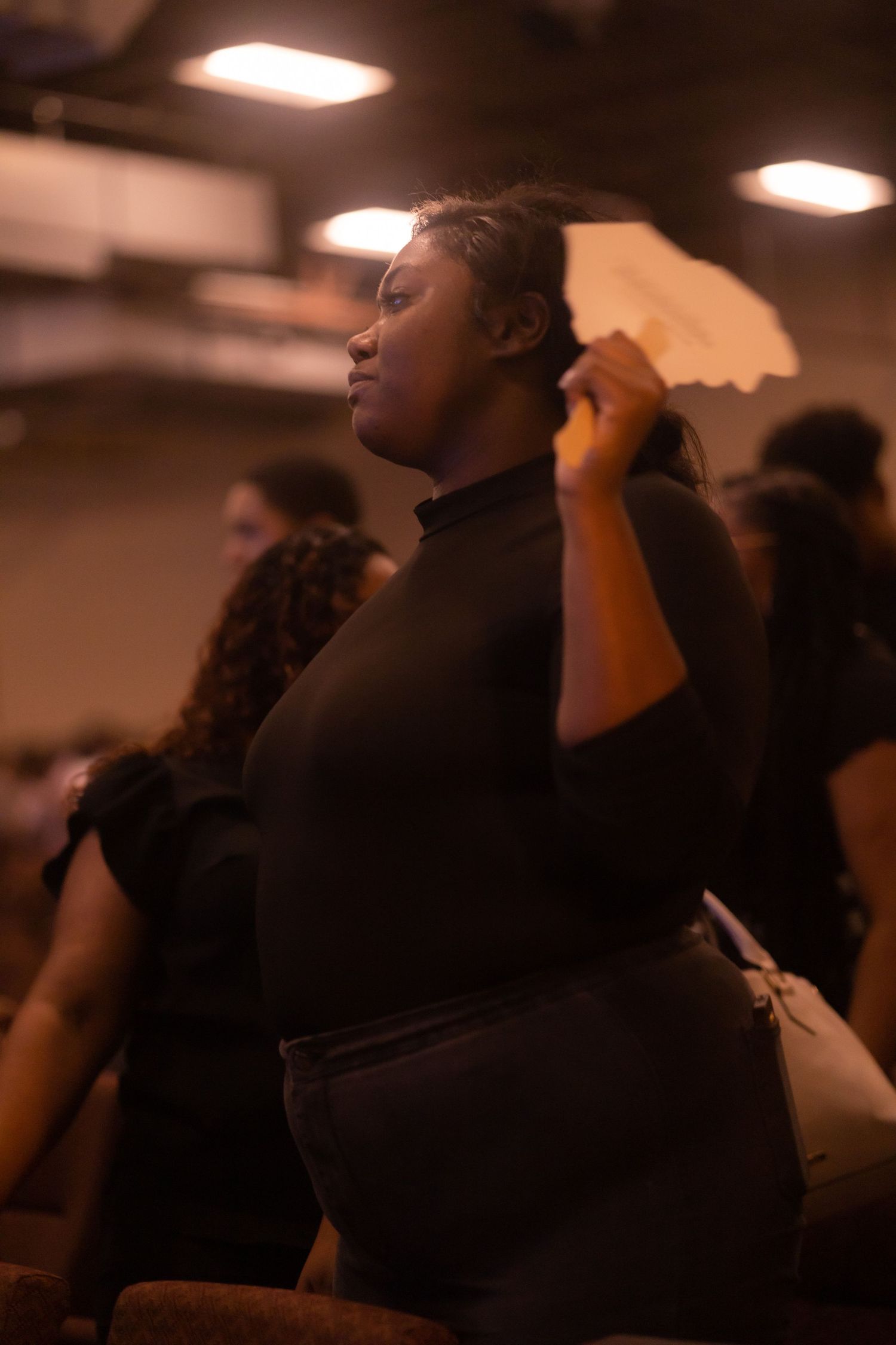 A person worships with eyes closed in a dimly lit indoor space.