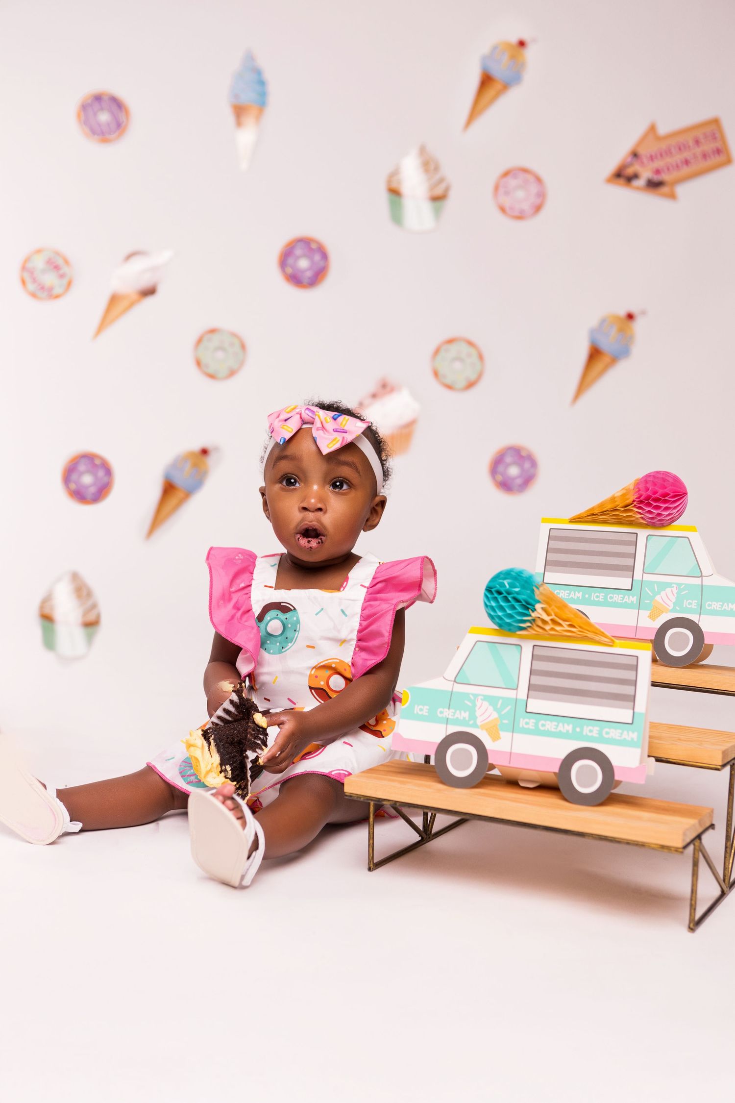 Sweet summer scene with ice cream cones and donuts on pink background with decorative toy trucks.
