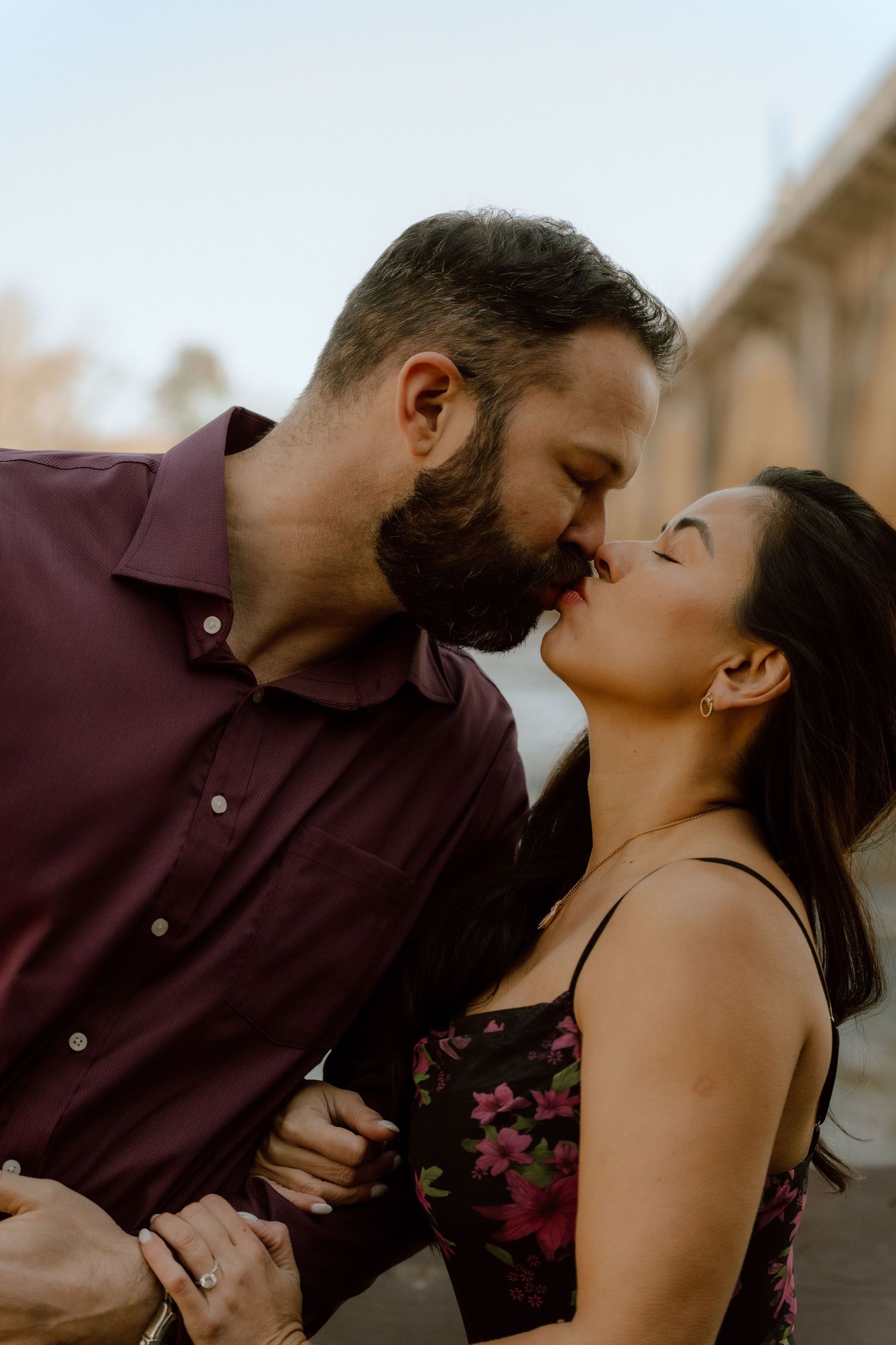 A romantic couple shares an intimate kiss outdoors during sunset.