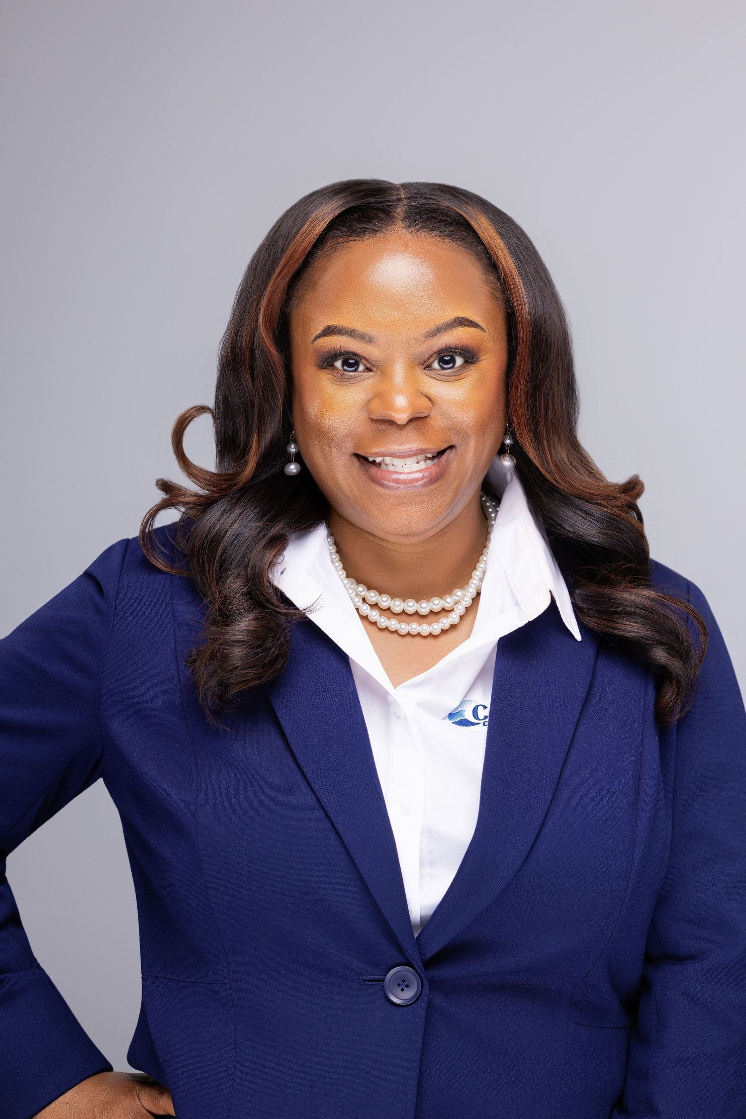 Professional headshot series showing a warm smile in a navy blazer and white blouse against a gray backdrop.