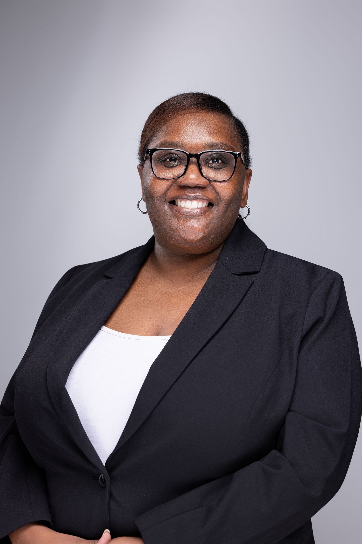 Professional headshot series showing warm expressions and confidence in a black blazer against a gray background.