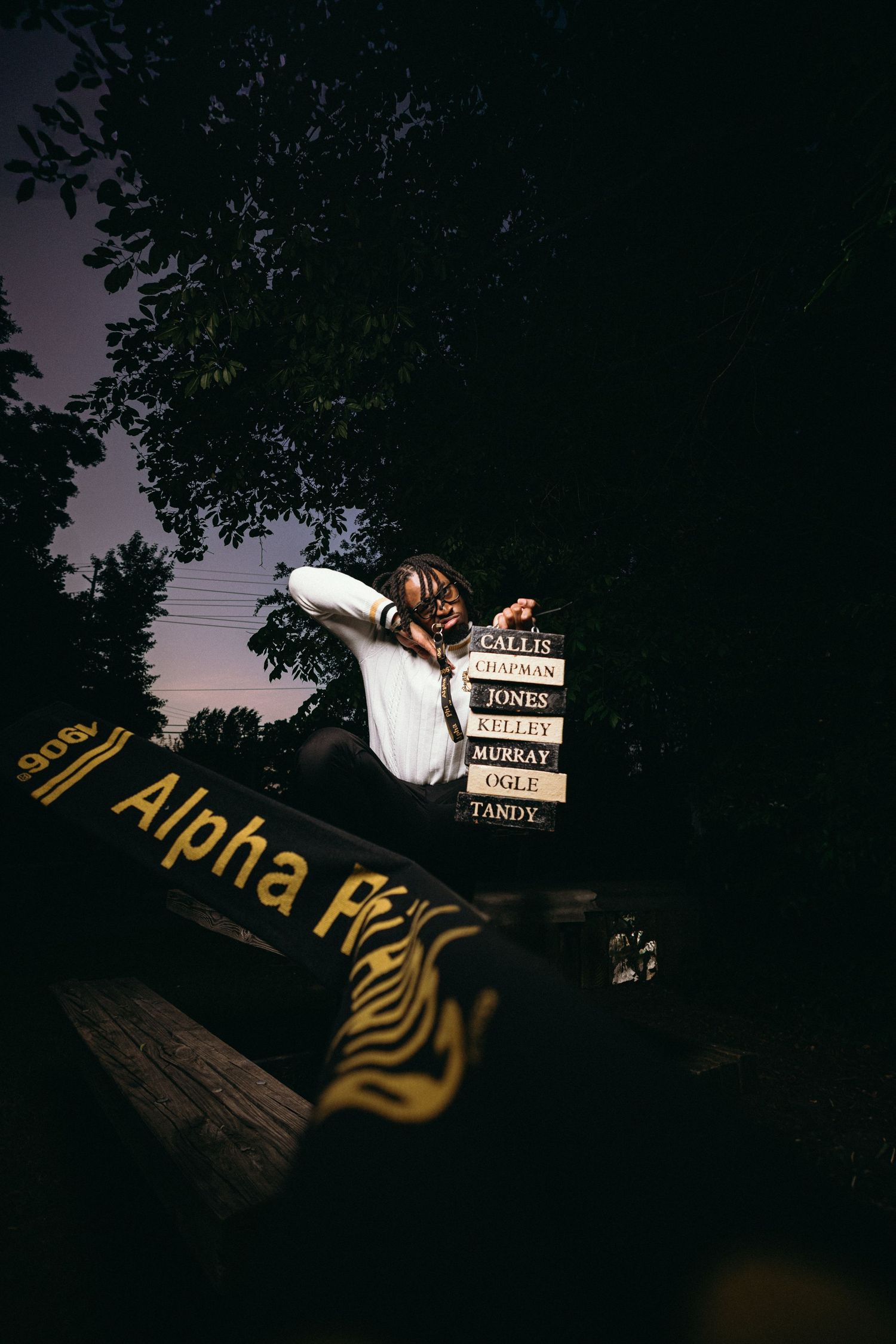 Dramatic nighttime photo showing 'Alpha Phi' text and stacked books in dark setting.