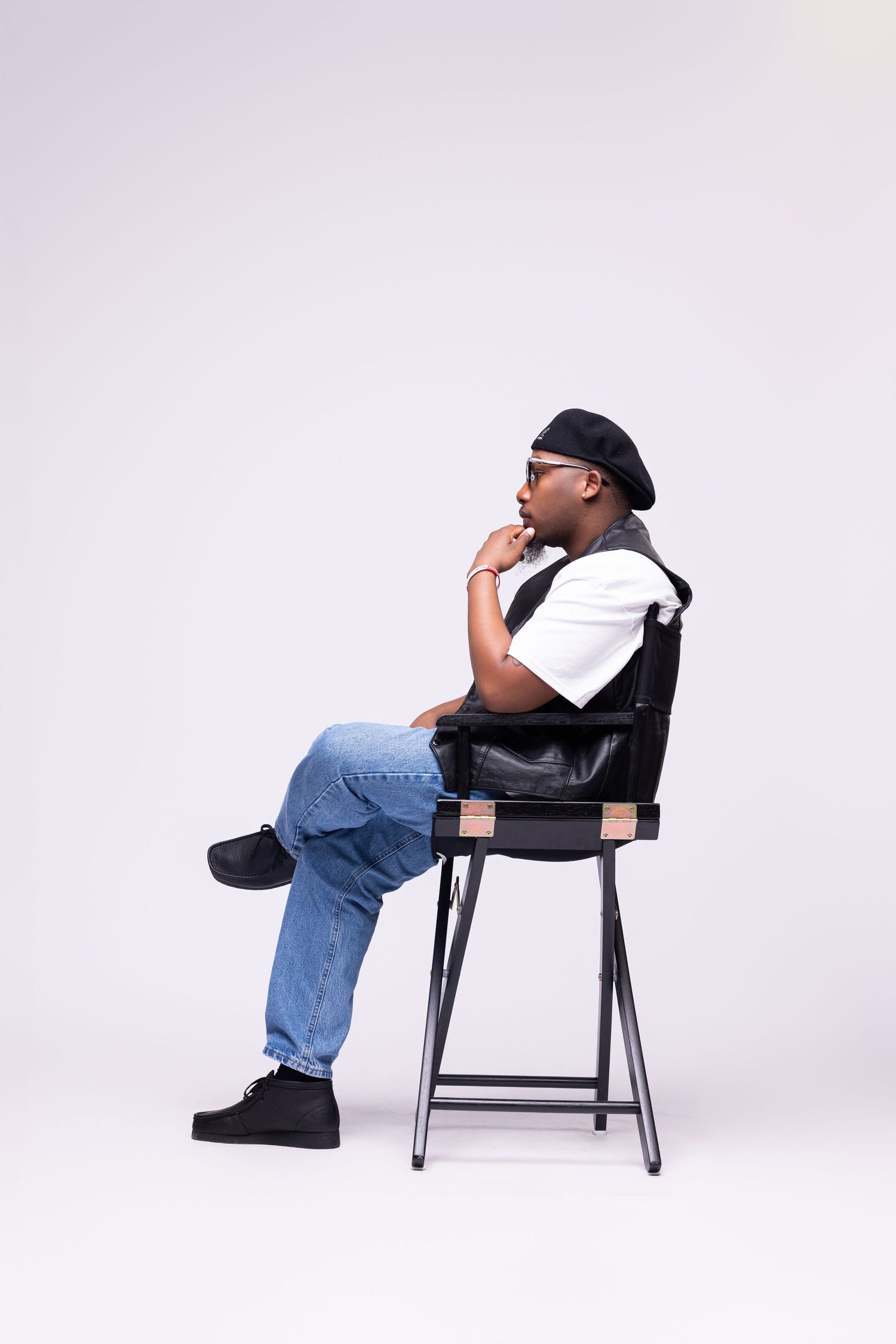 Multiple shots of someone relaxing on a black chair wearing casual denim and a cap.