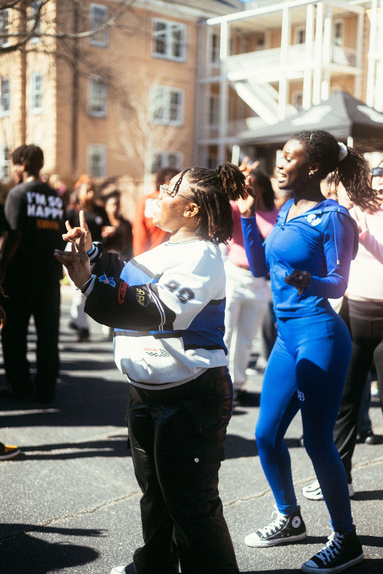 People dance and exercise together at an outdoor fitness class on a sunny day near a brick building. USC Hip Hop Wednesday
