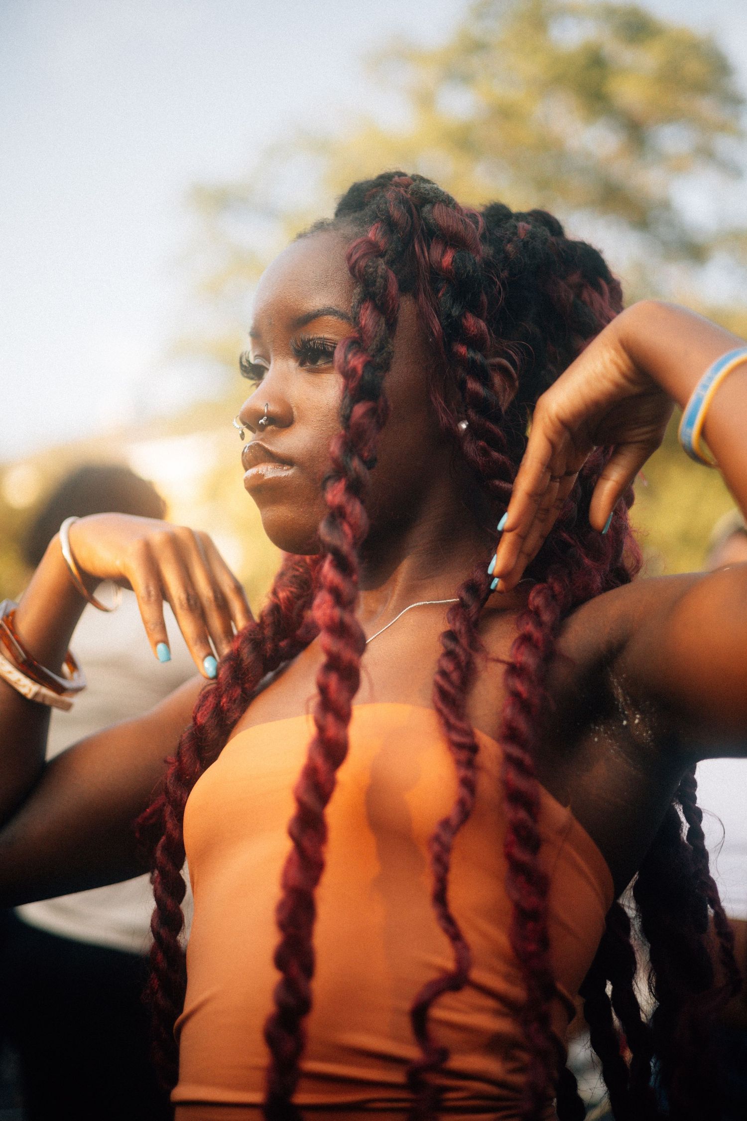 Profile silhouette wearing an orange top with burgundy braided hair in late afternoon sunlight.  USC Hip Hop Wednesday