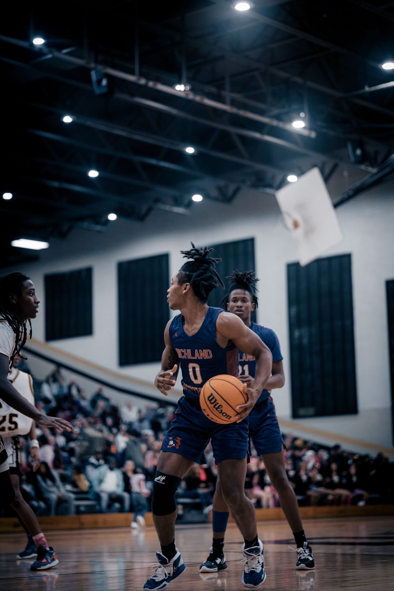 Basketball player in navy uniform dribbles ball during competitive indoor game.
