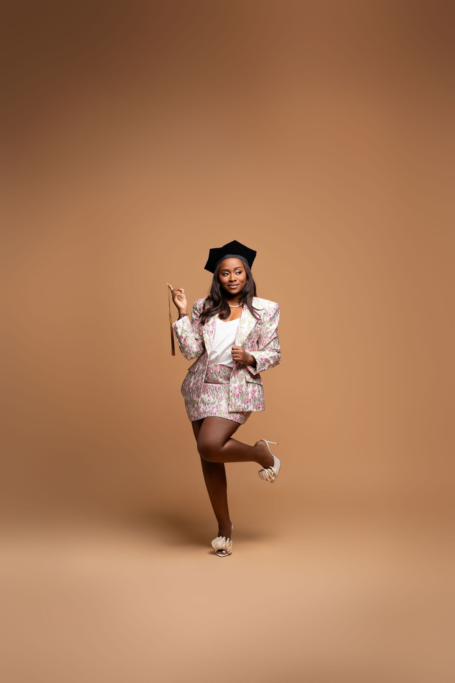 Young Black woman in sequined blazer and skirt with beret poses dynamically on beige background.