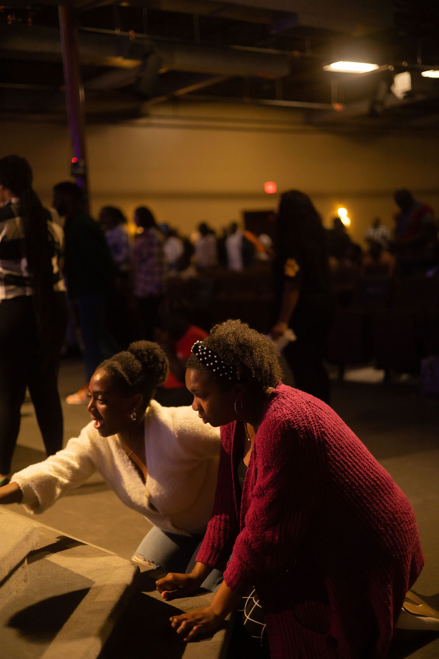 Two people lean over papers at a dimly lit table during what appears to be a meeting or planning session.